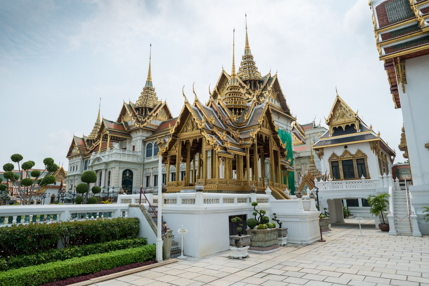Ornate Grand Palace complex in Bangkok featuring traditional Thai golden architecture and manicured gardens.