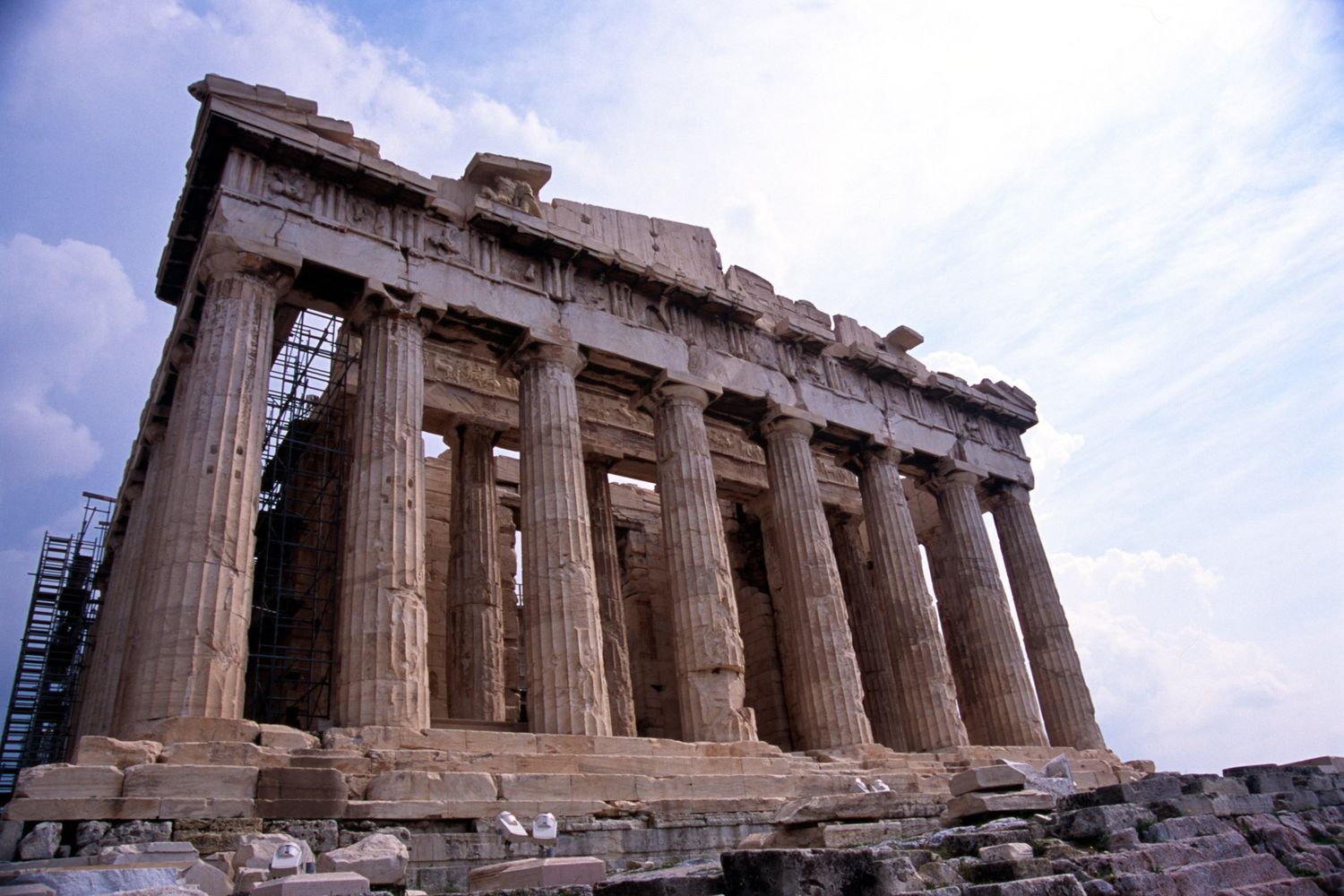 Ancient Parthenon temple on the Acropolis in Athens with tall columns against a cloudy sky.