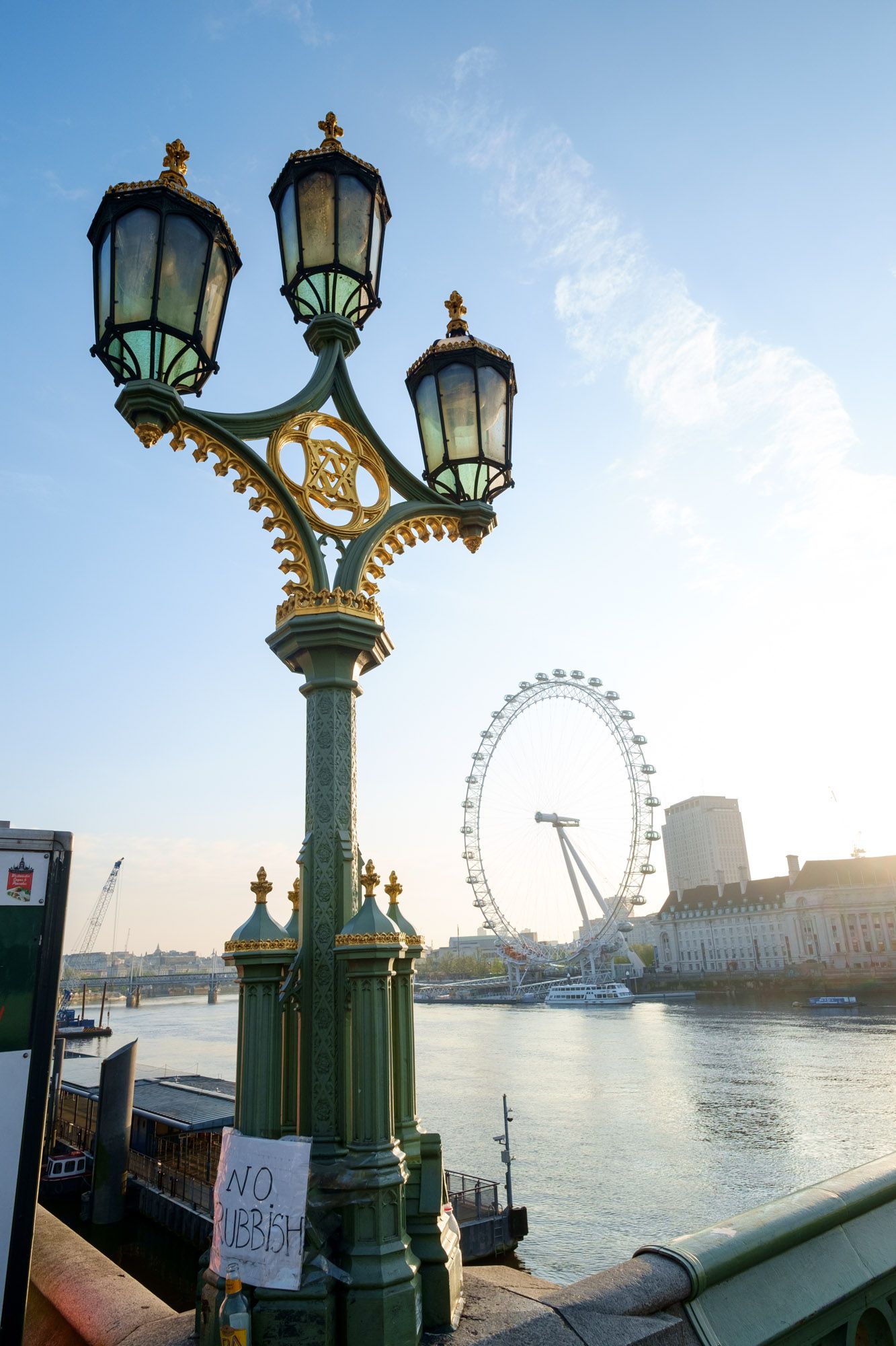 Decorative green and gold street lamp post on Westminster Bridge with London Eye visible in background.