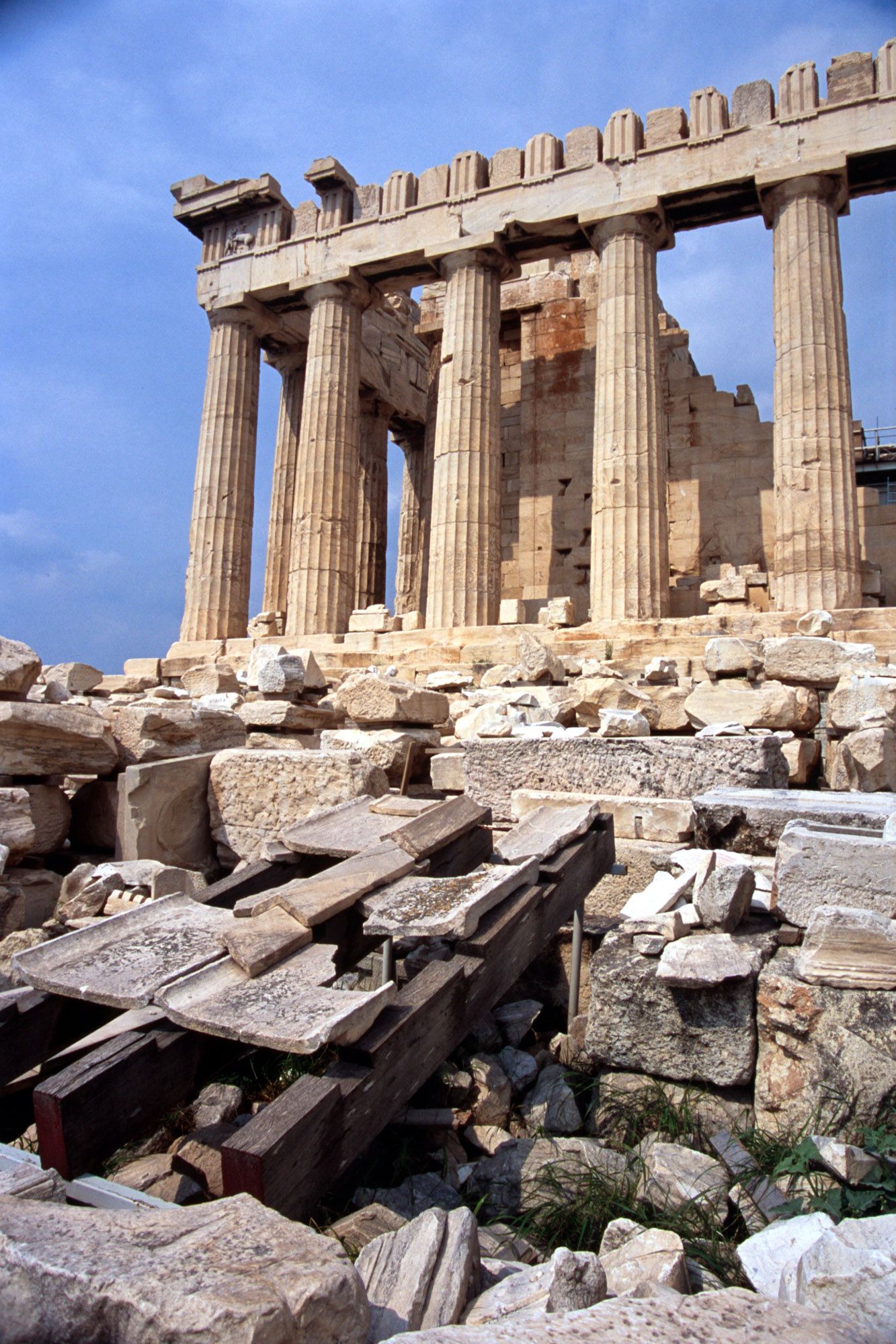 Iconic Parthenon columns and ancient ruins on the Acropolis of Athens under a blue sky.