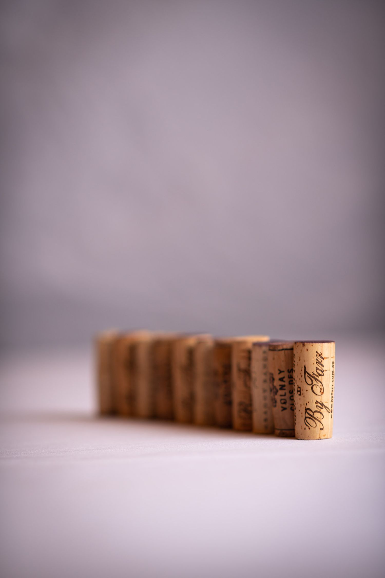 A row of wine corks lined up on a white surface with shallow depth of field.