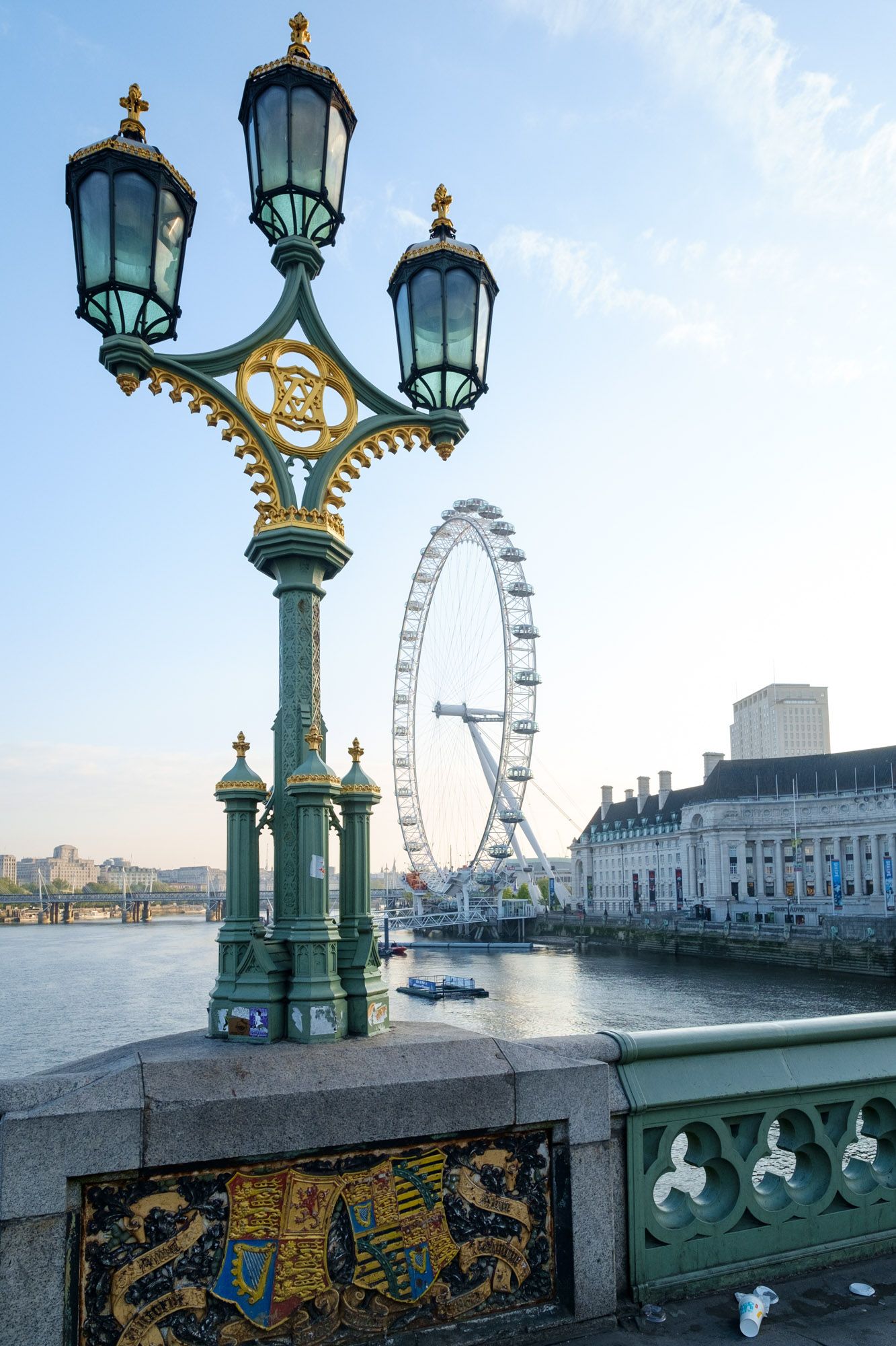 Ornate Victorian street lamp on Westminster Bridge with London Eye ferris wheel and Thames River behind.