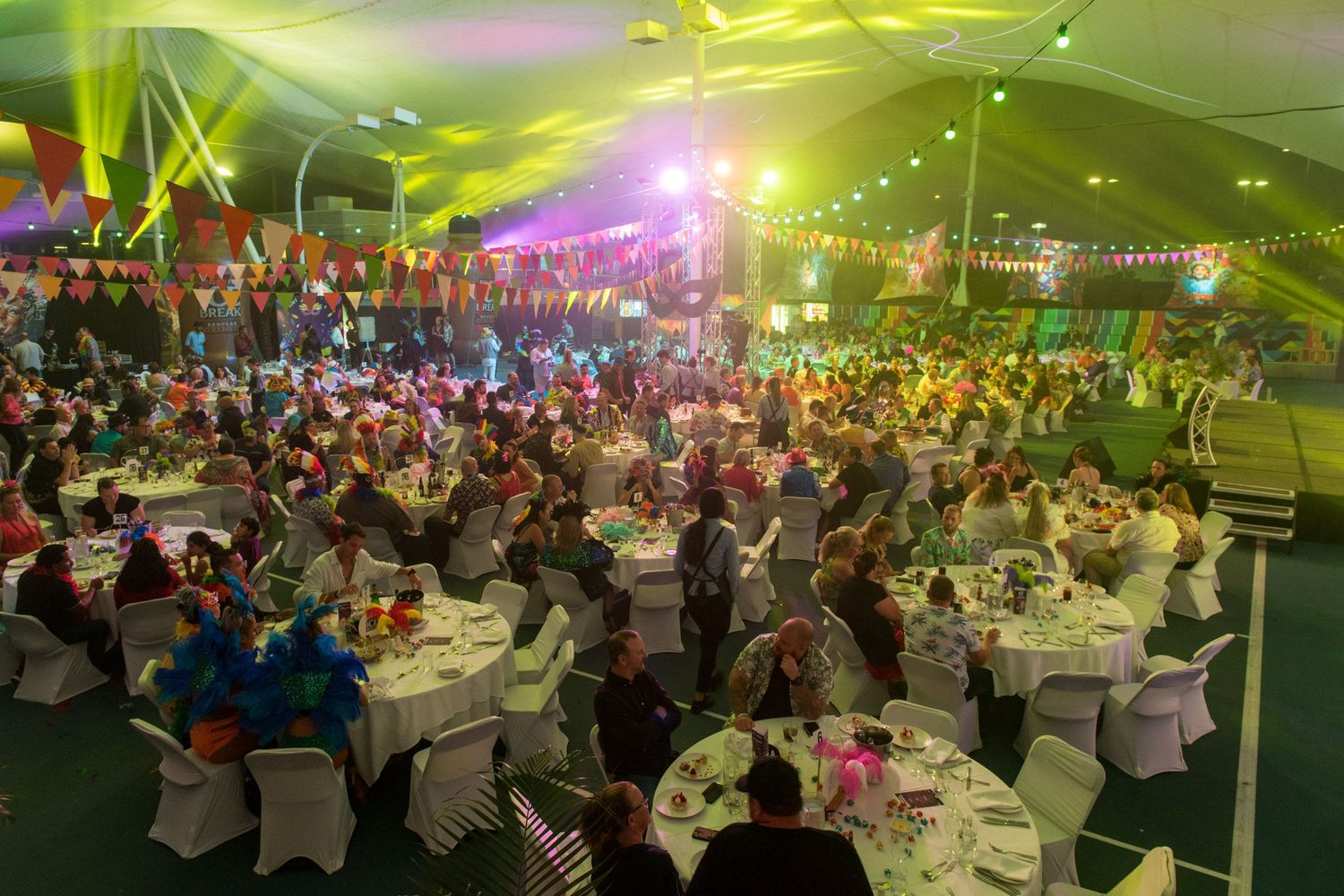 Large gala dinner event under decorated tent with round tables.