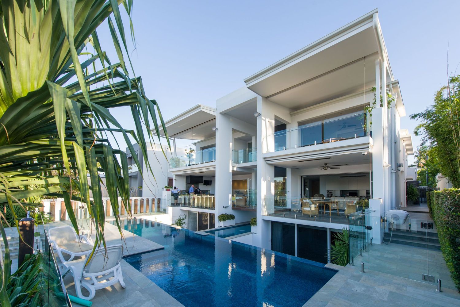 Luxury modern home with swimming pool, balconies, and tropical landscaping.