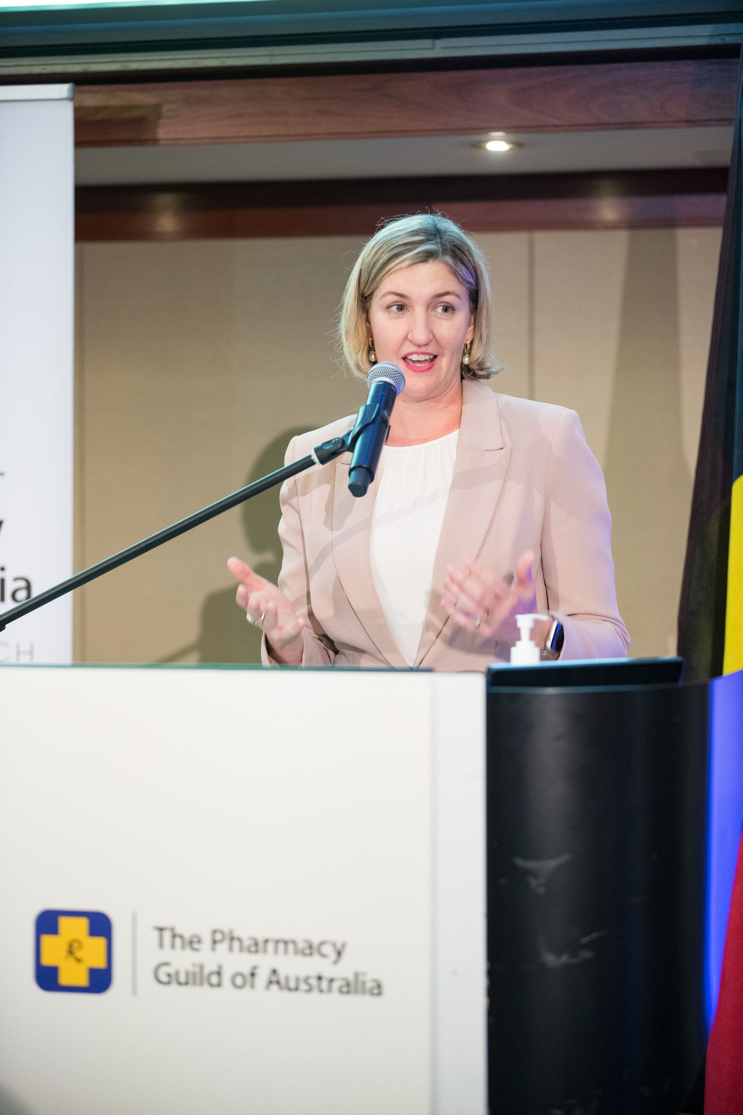 Female speaker presenting at a podium for The Pharmacy Guild of Australia corporate conference event.