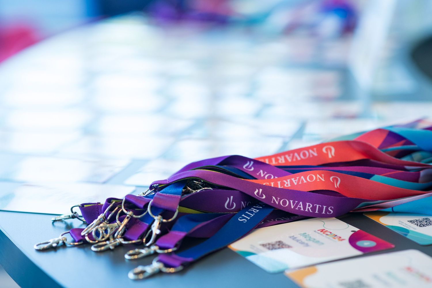 Novartis branded lanyards and name badges arranged on a registration table at NC24 conference.