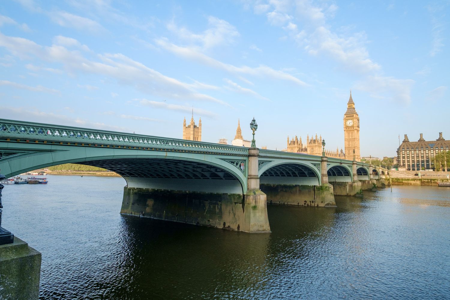 Westminster Bridge spanning the River Thames with Big Ben and Houses of Parliament in London at dusk.