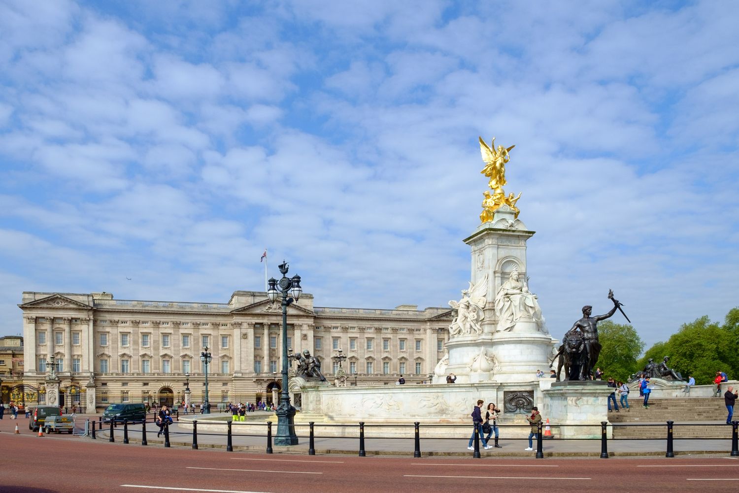 Buckingham Palace with Victoria Memorial statue under partly cloudy blue sky in London.