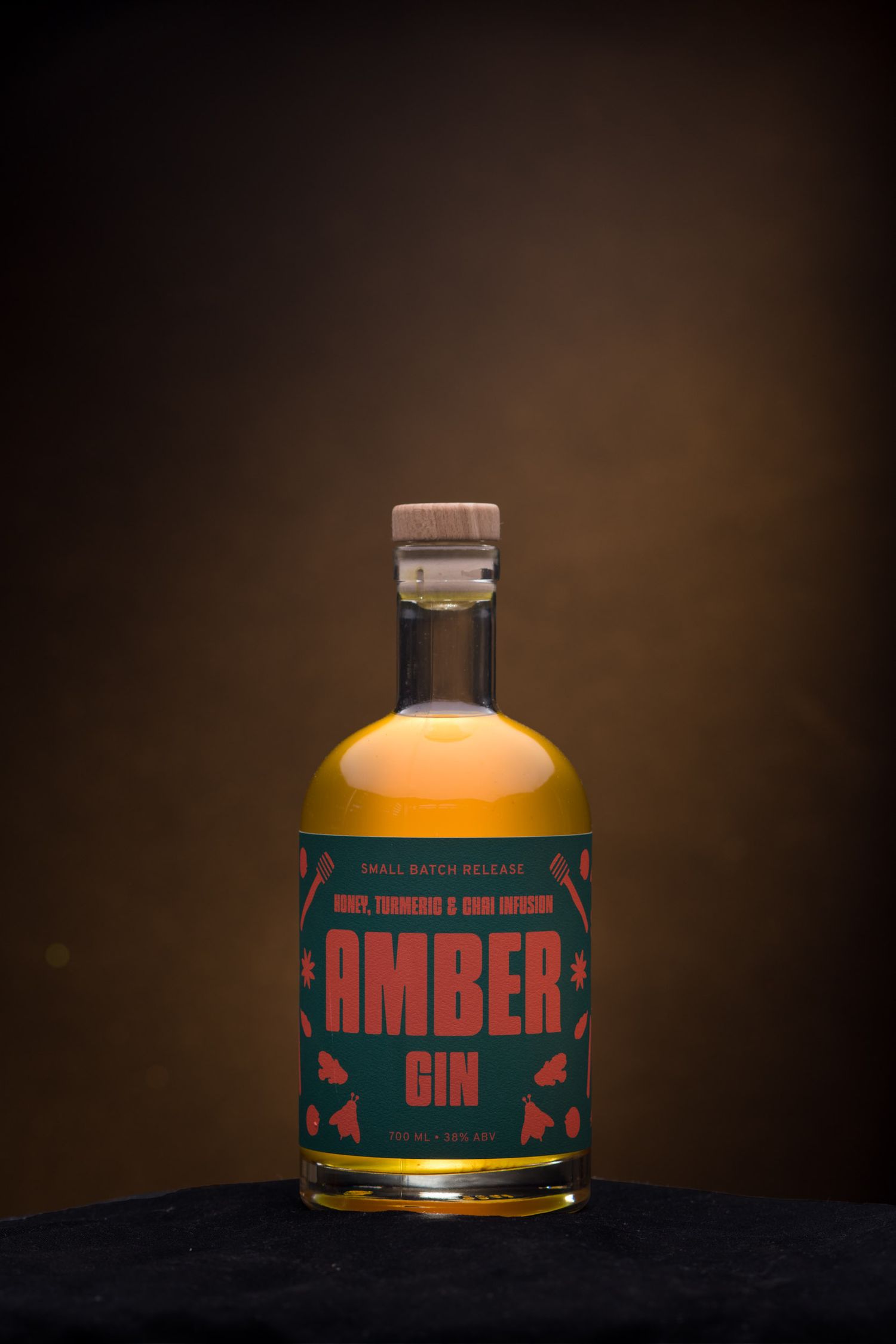 Amber Gin bottle with honey, turmeric and chai infusion on dark background.