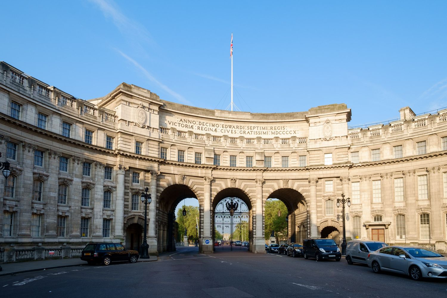 Admiralty Arch, a grand curved stone landmark in London, featuring three arched gateways under a clear blue sky.