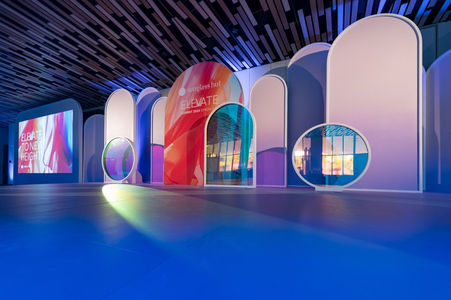 Vibrant event space with glowing arched panels, circular porthole windows, and blue floor lighting.