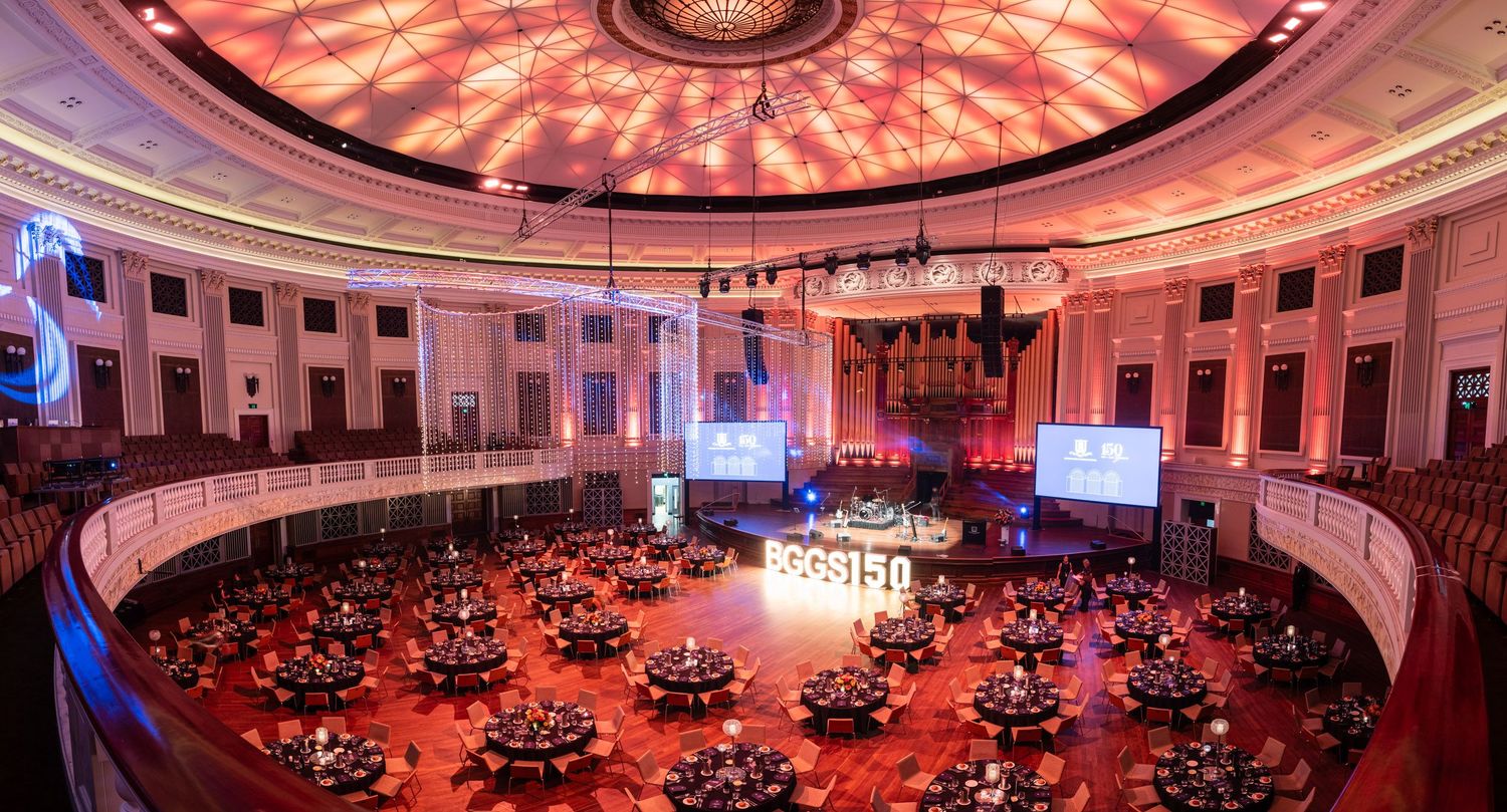 Aerial view of elegant grand hall with round ceiling, red decor, and round dining tables at event.