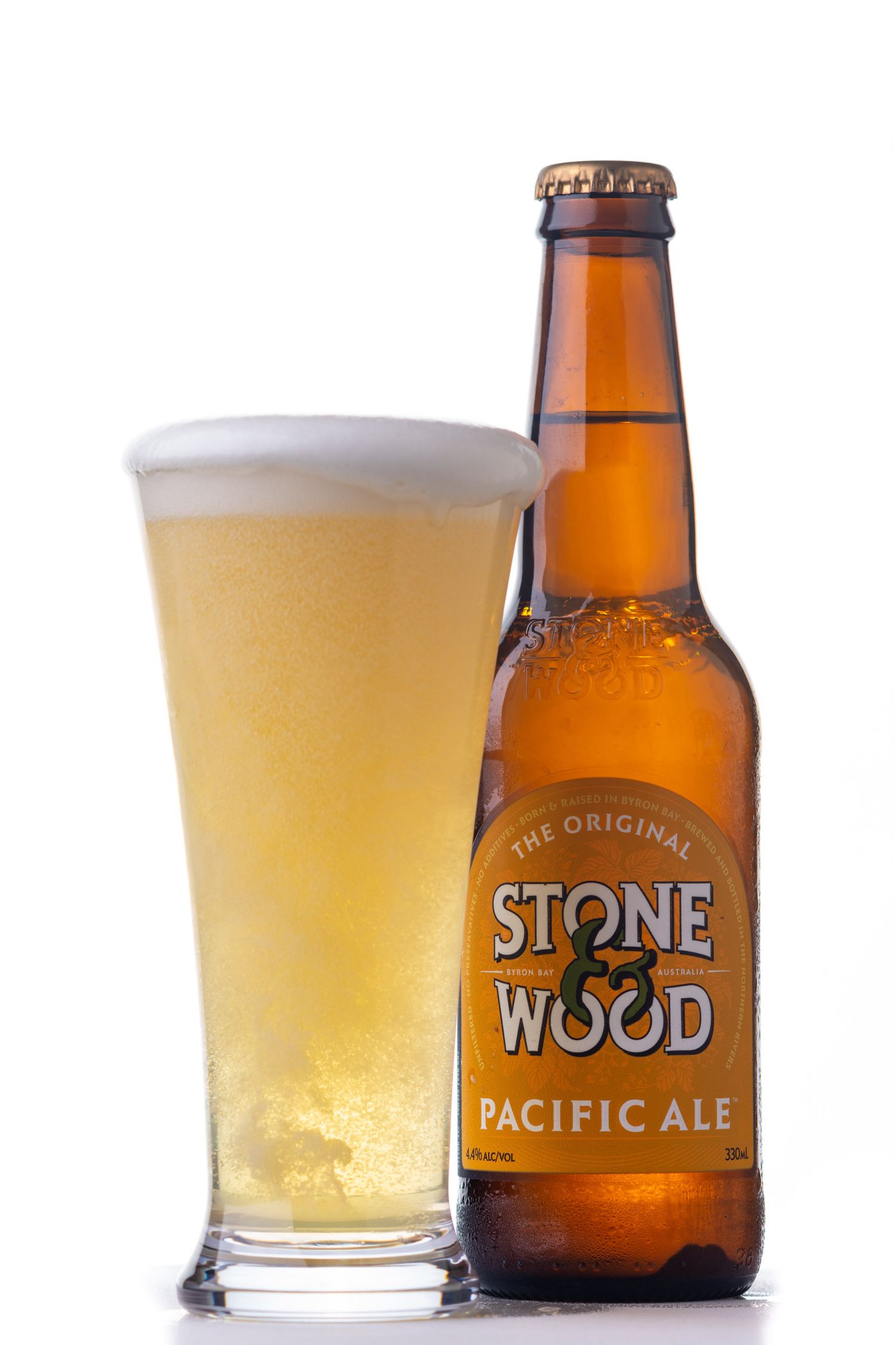 Stone and Wood Pacific Ale bottle beside a full pint glass on white background.