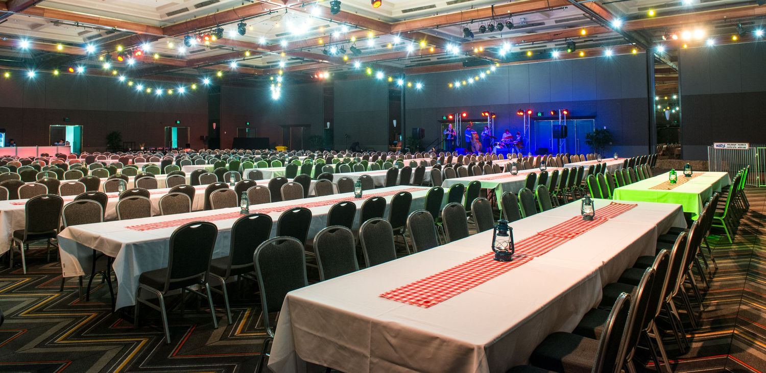 Large banquet hall set with long white-clothed tables and chairs for a formal dinner event.