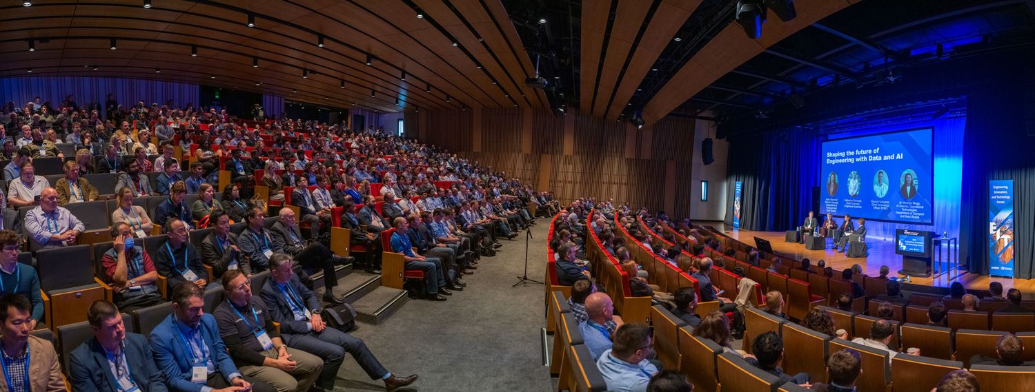 Panoramic view of packed auditorium audience at engineering and technology conference event.