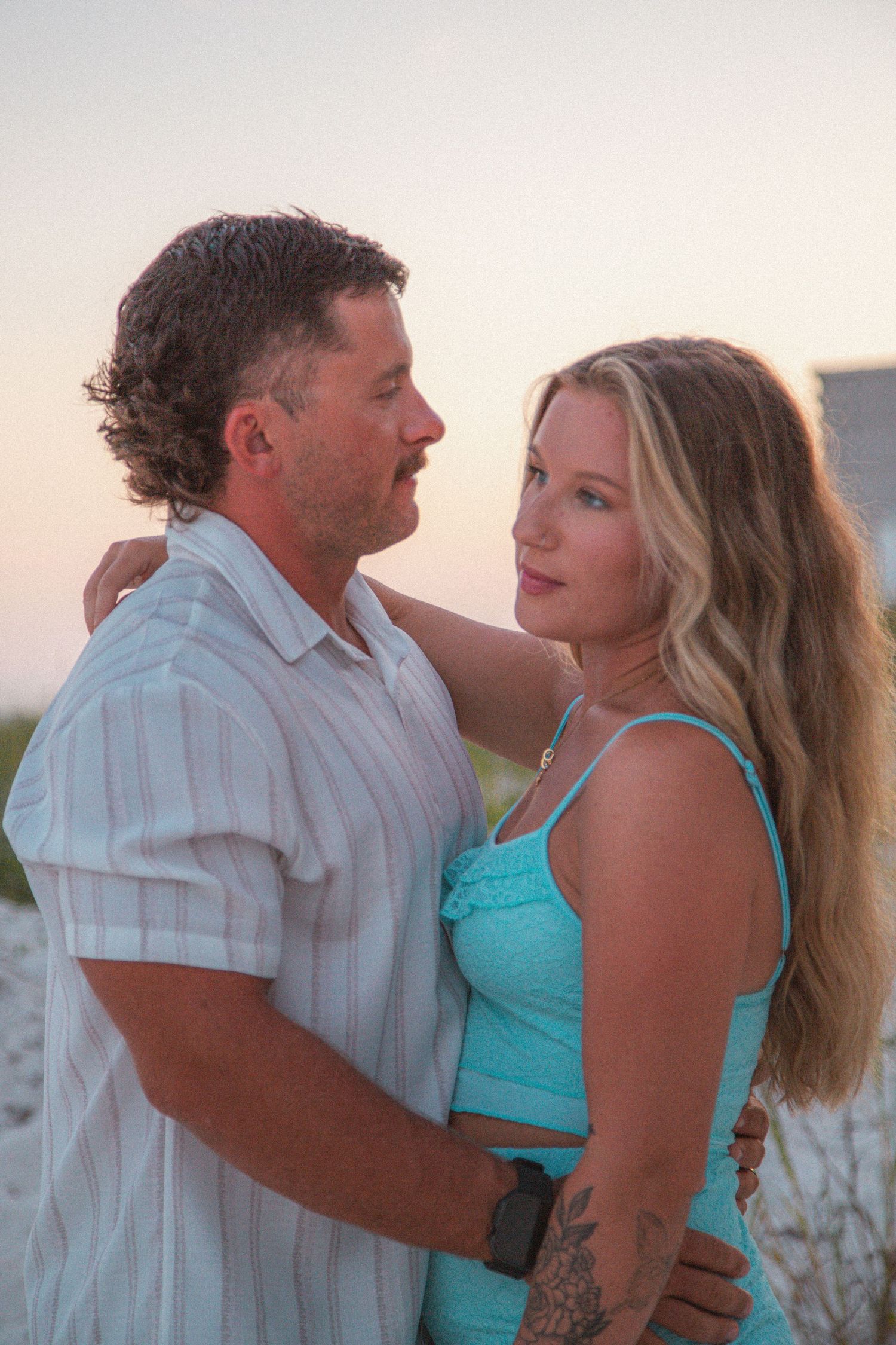 Couple holding each other close at beach during golden hour sunset.