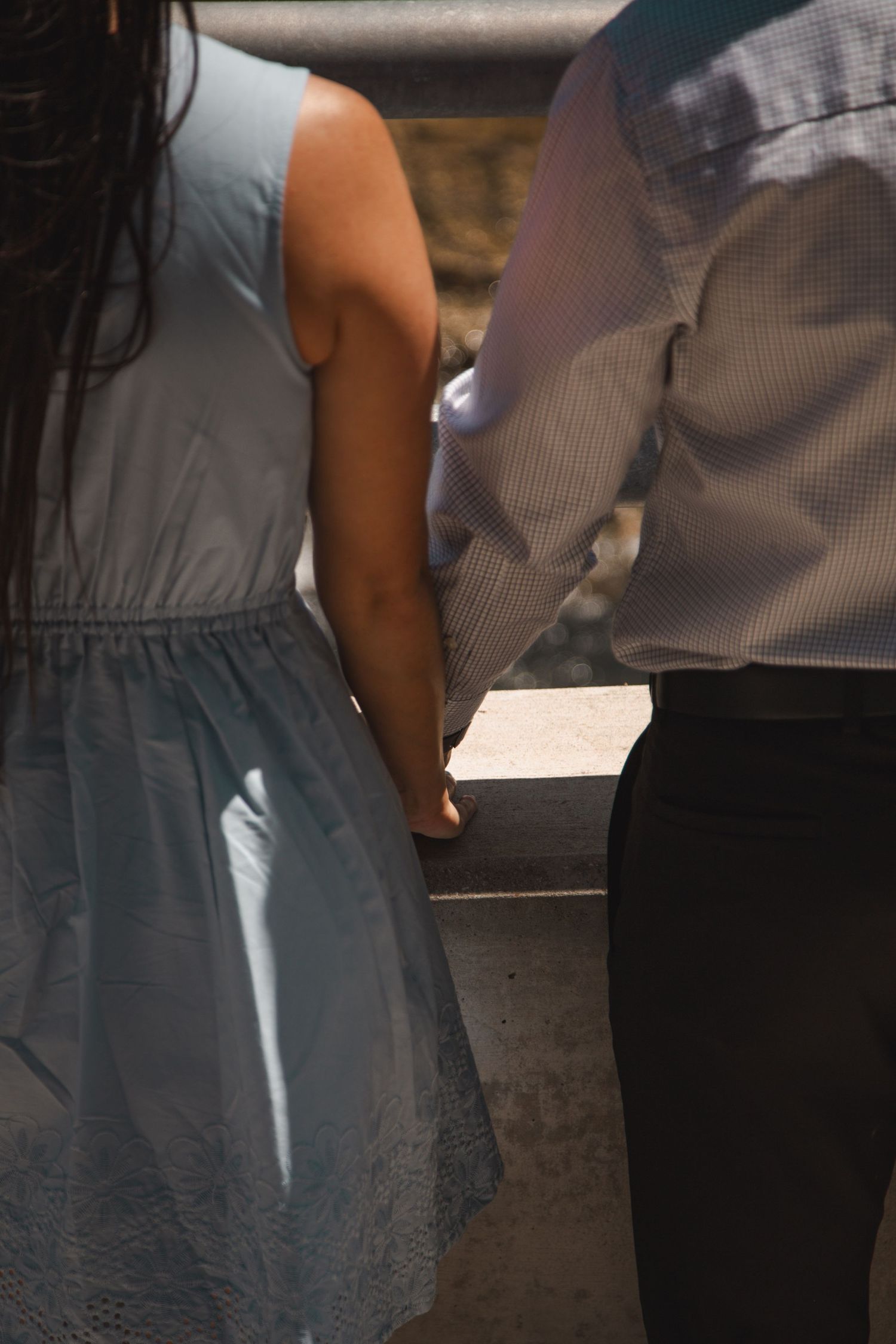 Couple holding hands in matching blue outfits, viewed from behind.