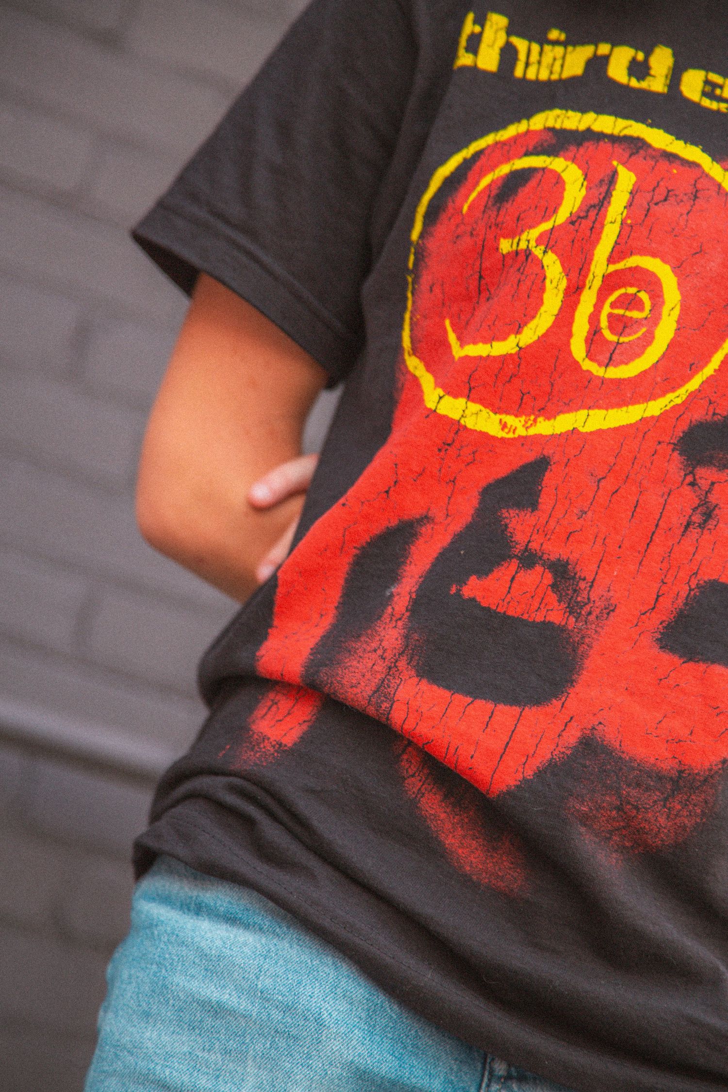 Close-up detail shot of a Third Eye Blind band t-shirt worn with denim shorts.
