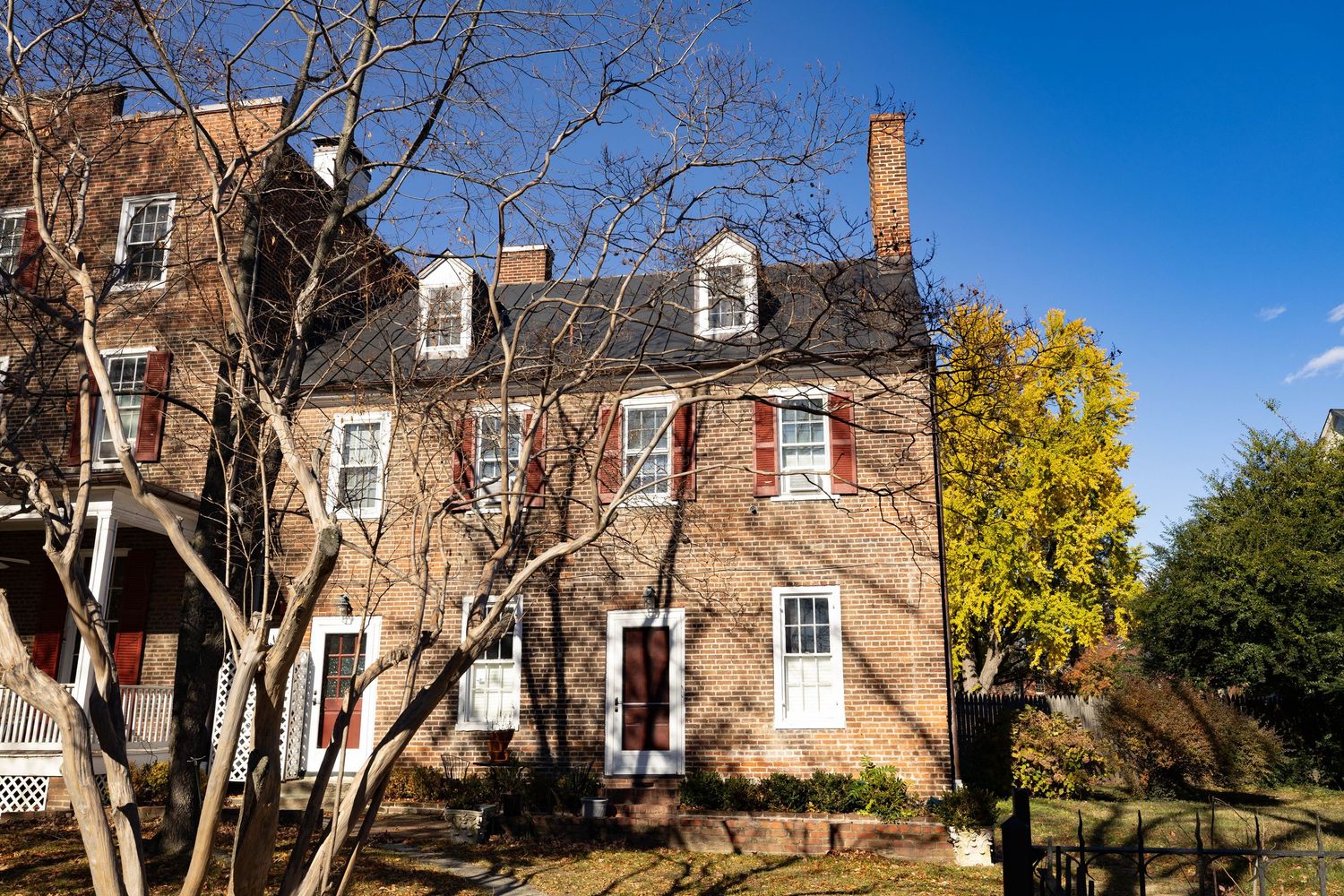 Historic brick residential building partially framed by a tree