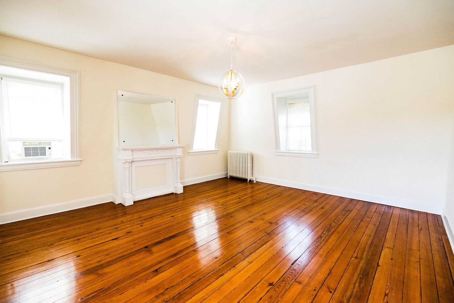 Bright upper-floor living space with hardwood floors and multiple windows
