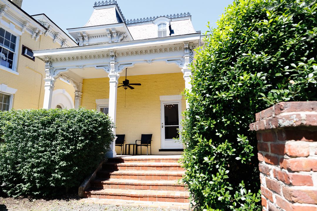 Covered back porch and brick steps surrounded by mature landscaping