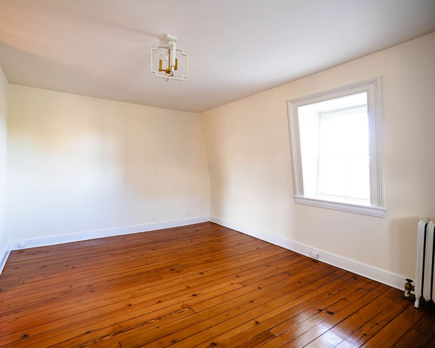 Empty bedroom with hardwood floors and natural window light