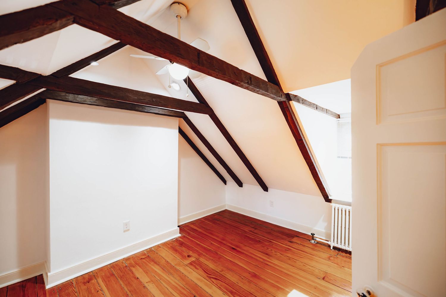 Upper-level bedroom with exposed wood ceiling beams and hardwood floors
