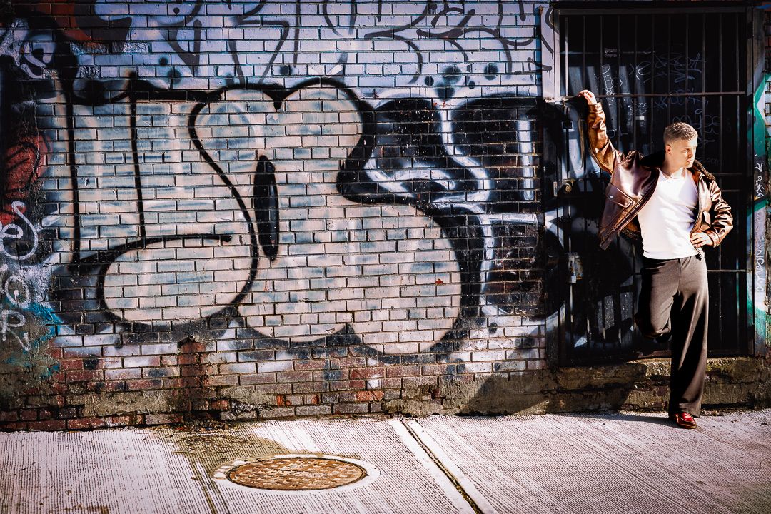 Urban portrait of a man posing against a graffiti-covered wall