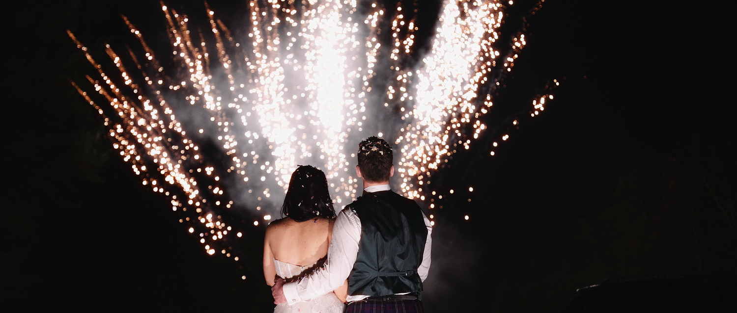 Bride and groom watching a spectacular fireworks display together on their wedding night.
