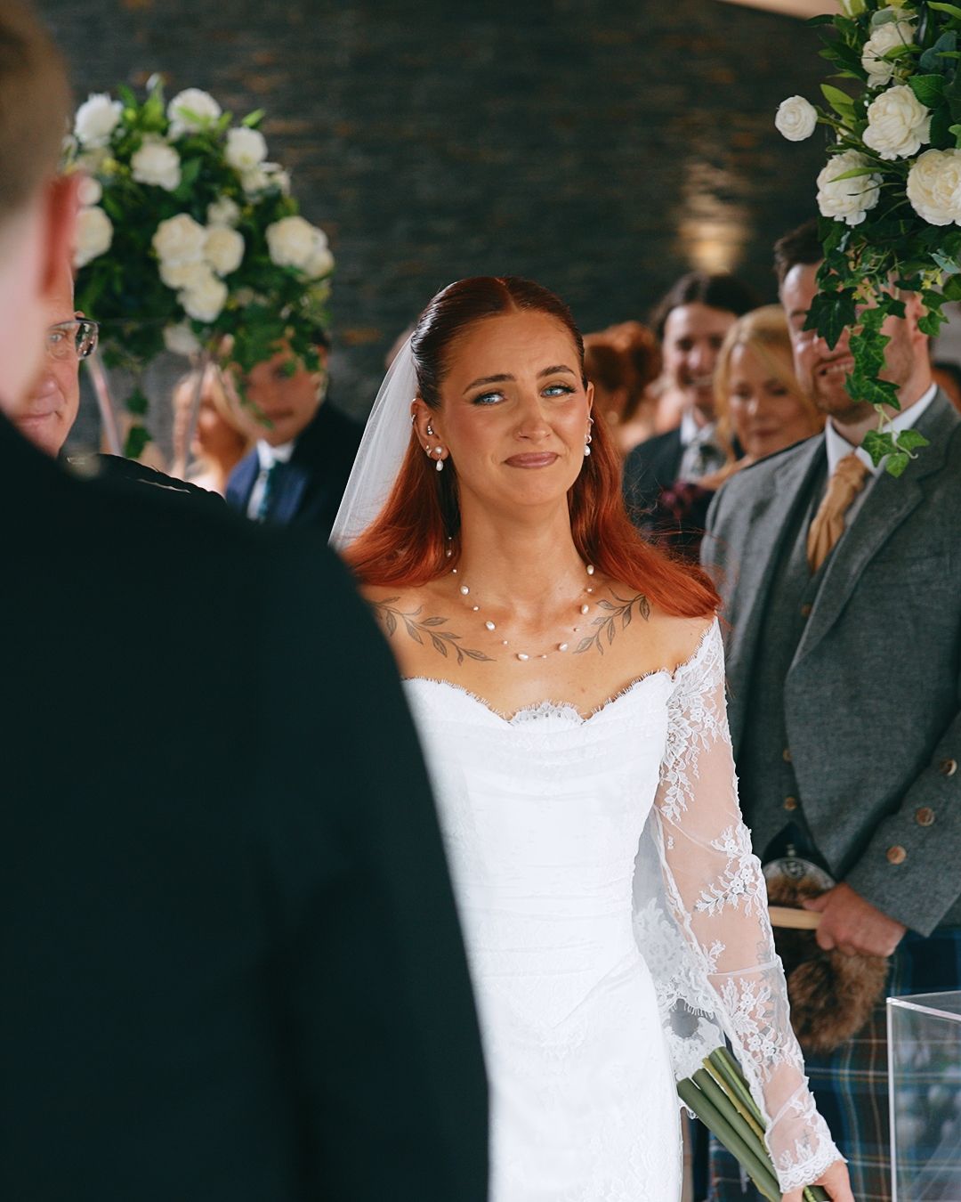 Emotional red-haired bride in lace wedding dress standing at the altar during her ceremony.