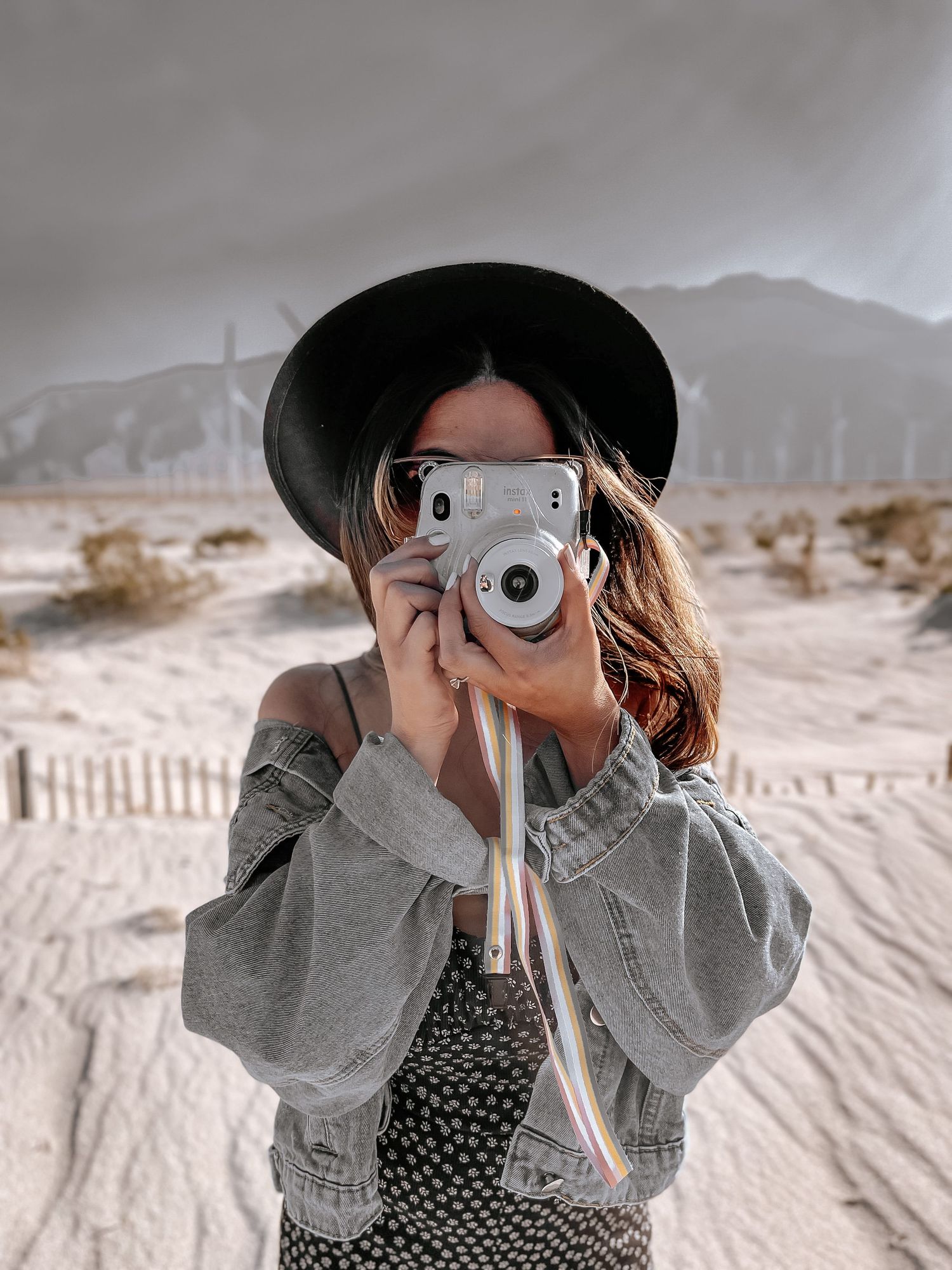 Palm Springs lifestyle photo in the desert with a woman holding a polaroid camera.