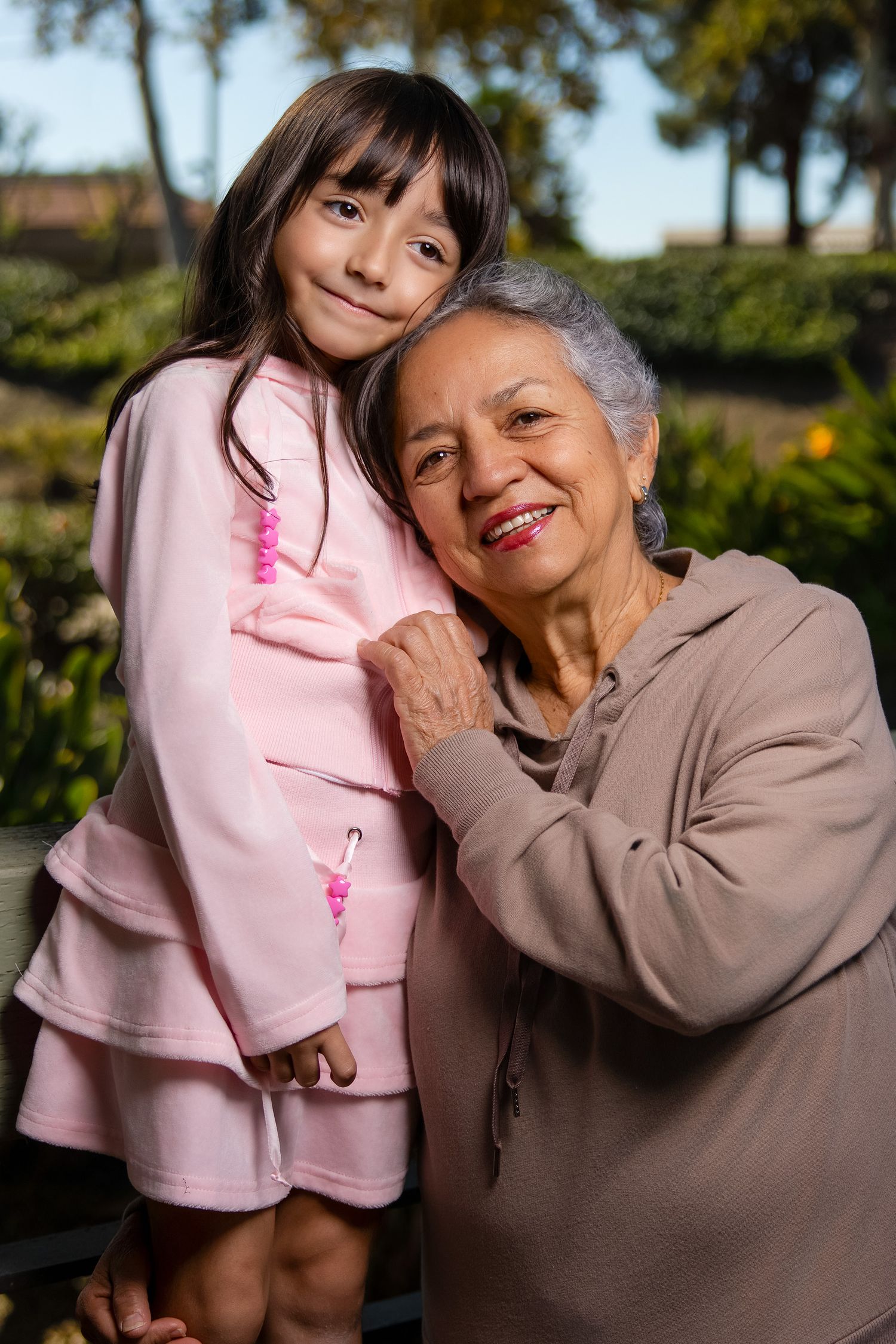 Heartwarming moment between child in pink sweater and elderly woman outdoors.