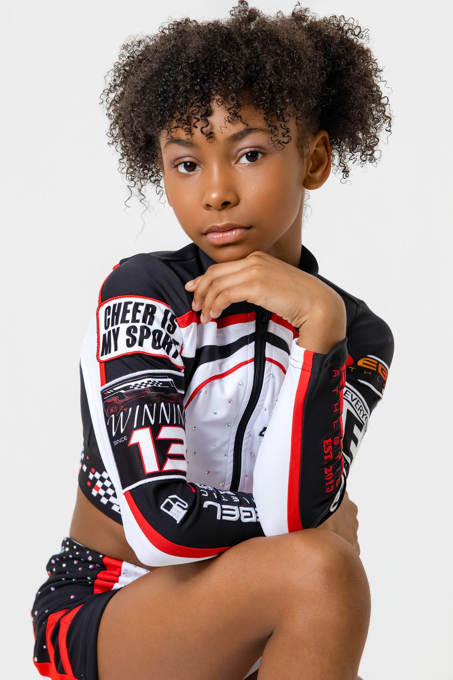 Young athlete in black and white sports gear posing confidently with crossed arms.