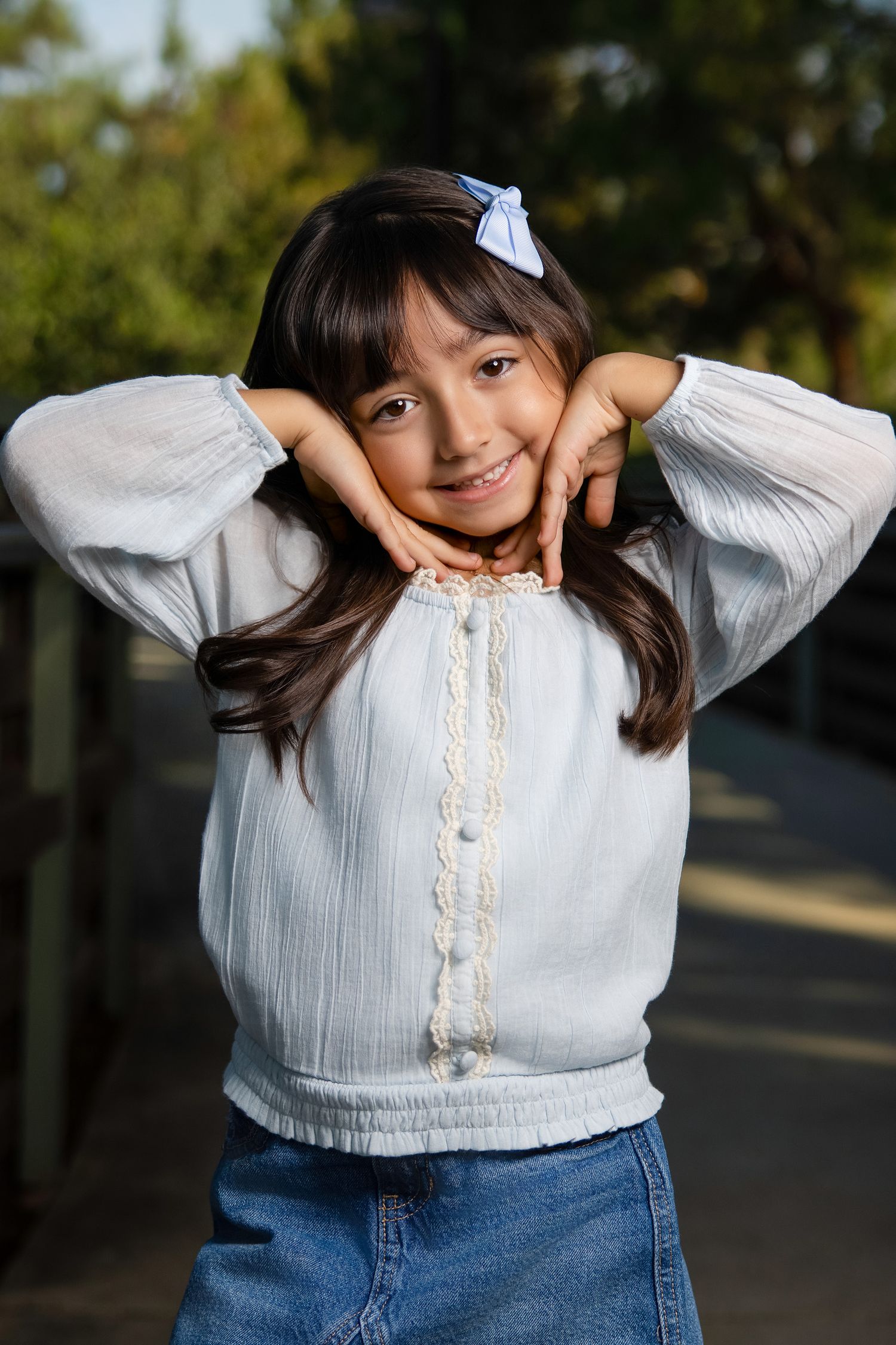 Person in white blouse with lace detail poses playfully outdoors.