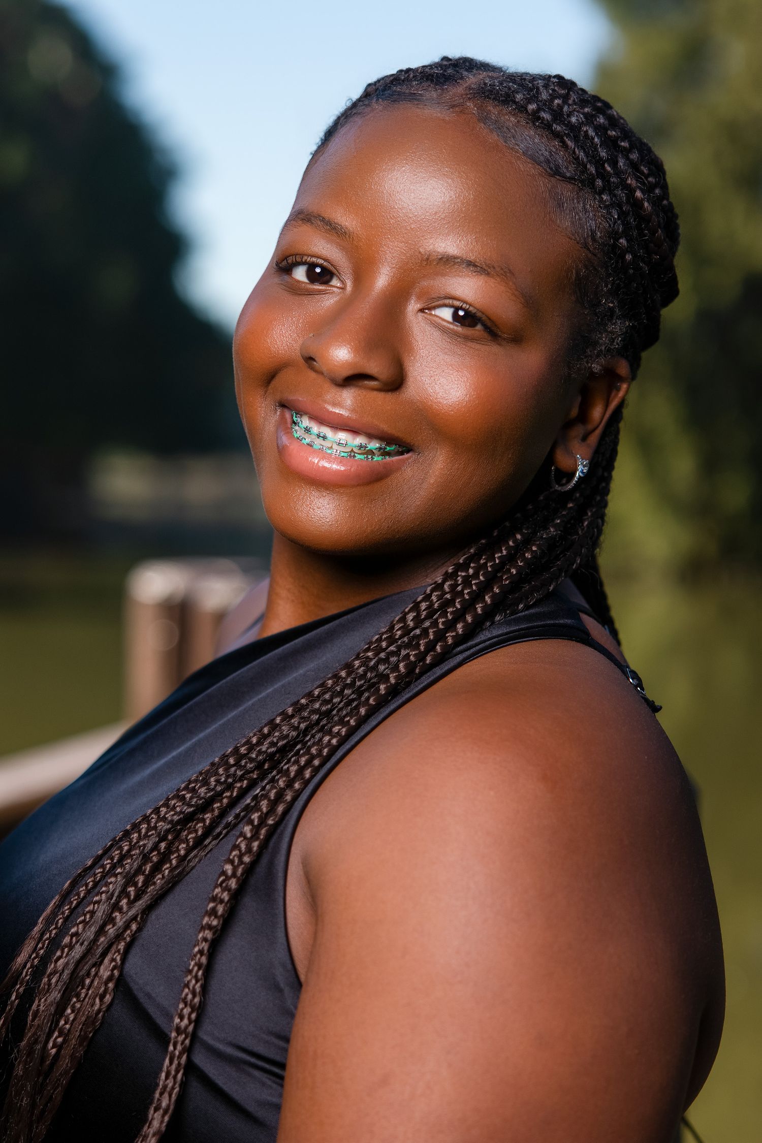 A portrait series showing someone with braided hair and braces wearing a black top against a blurred outdoor background.
