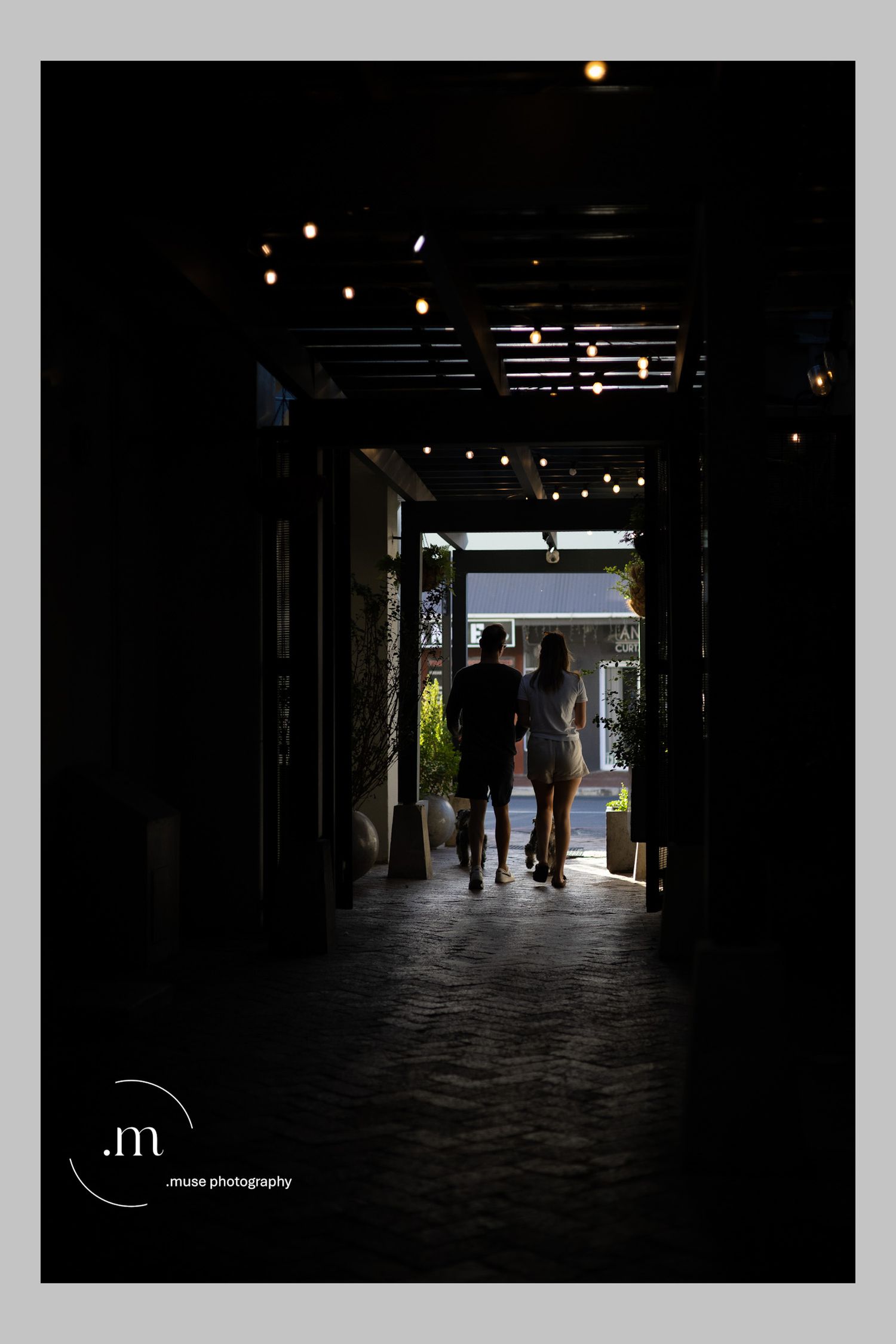 Silhouetted figures walking through a dark architectural passage