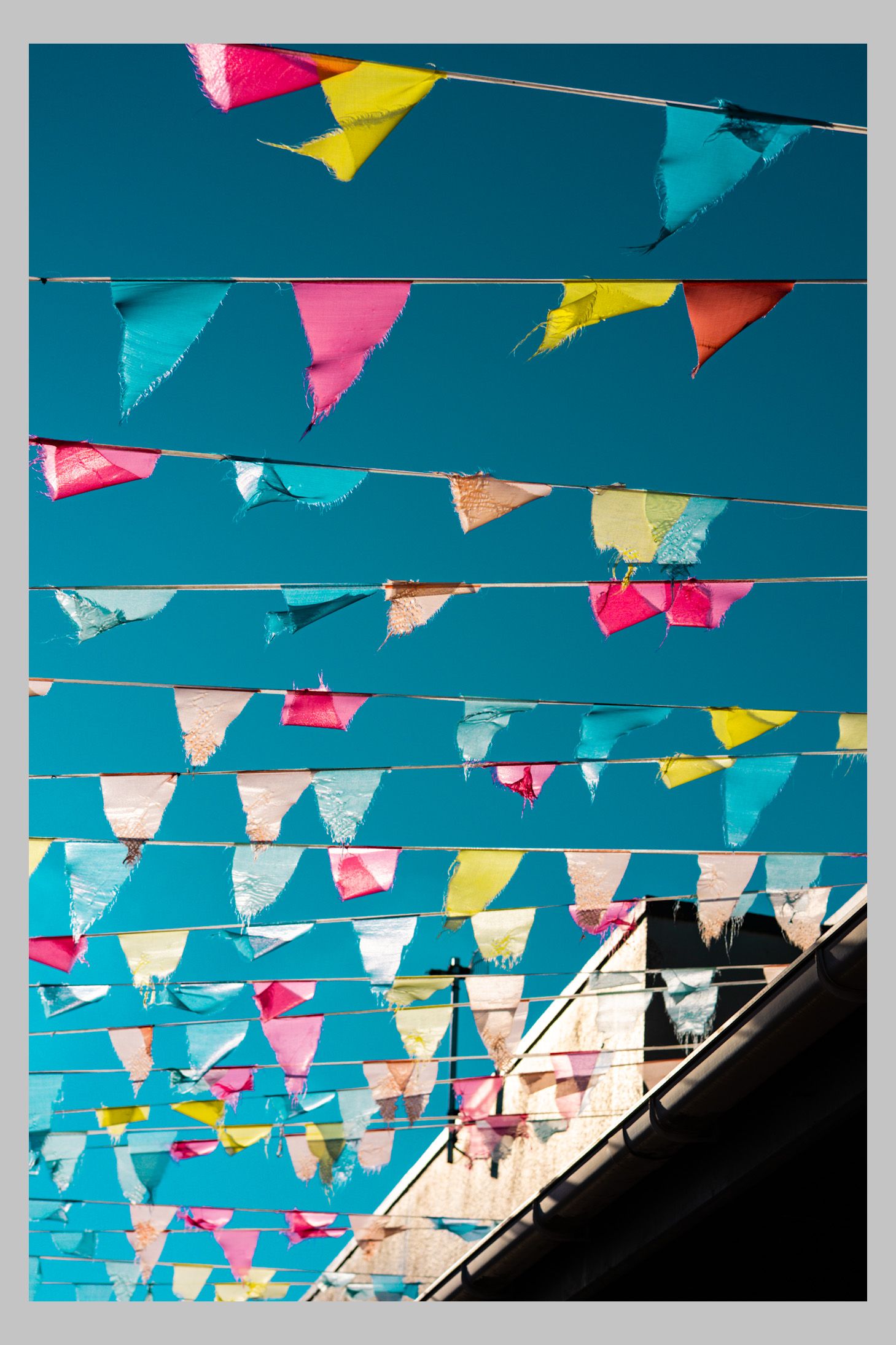Colorful hanging flags against a bright blue sky