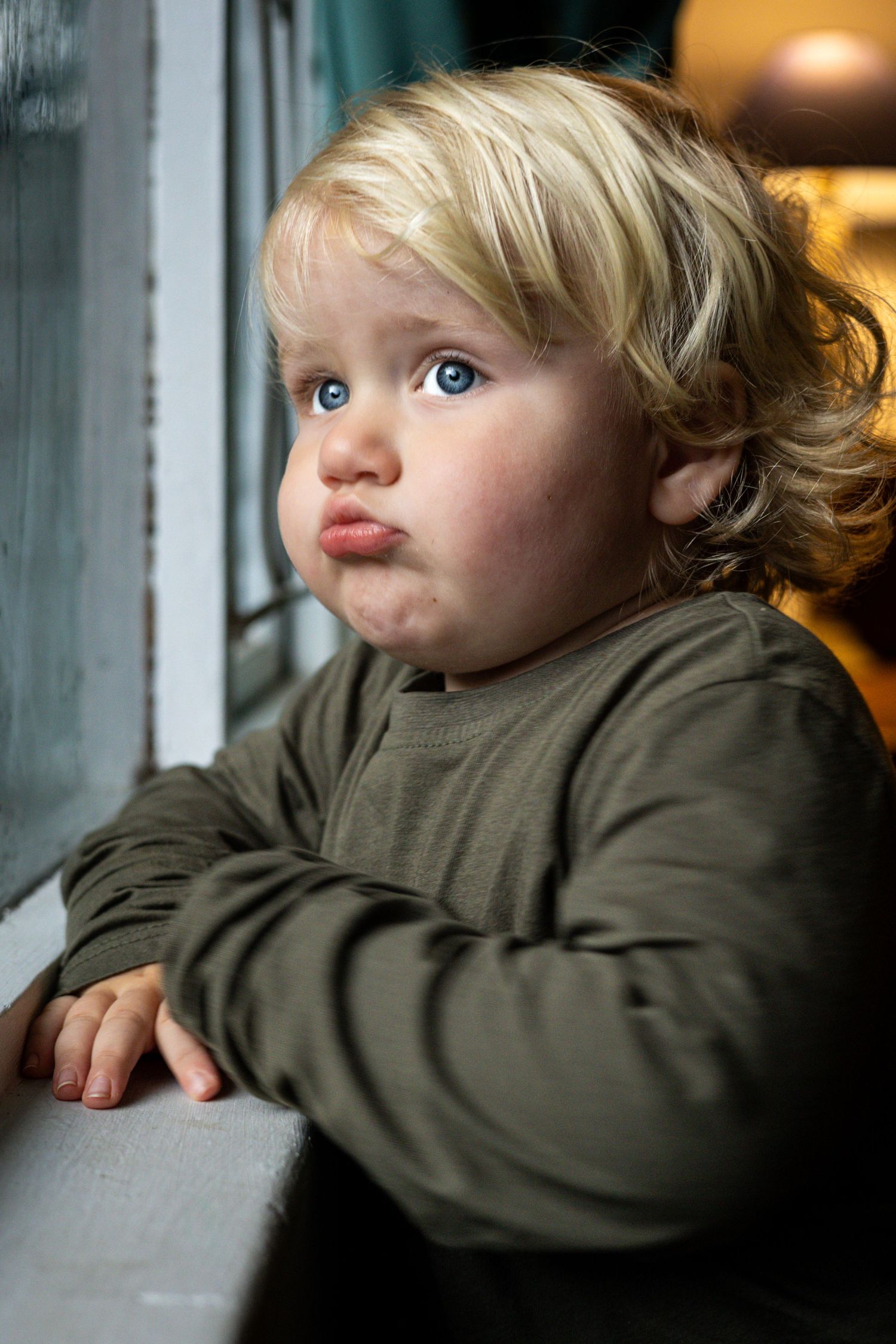 Toddler looking out a window with soft natural light