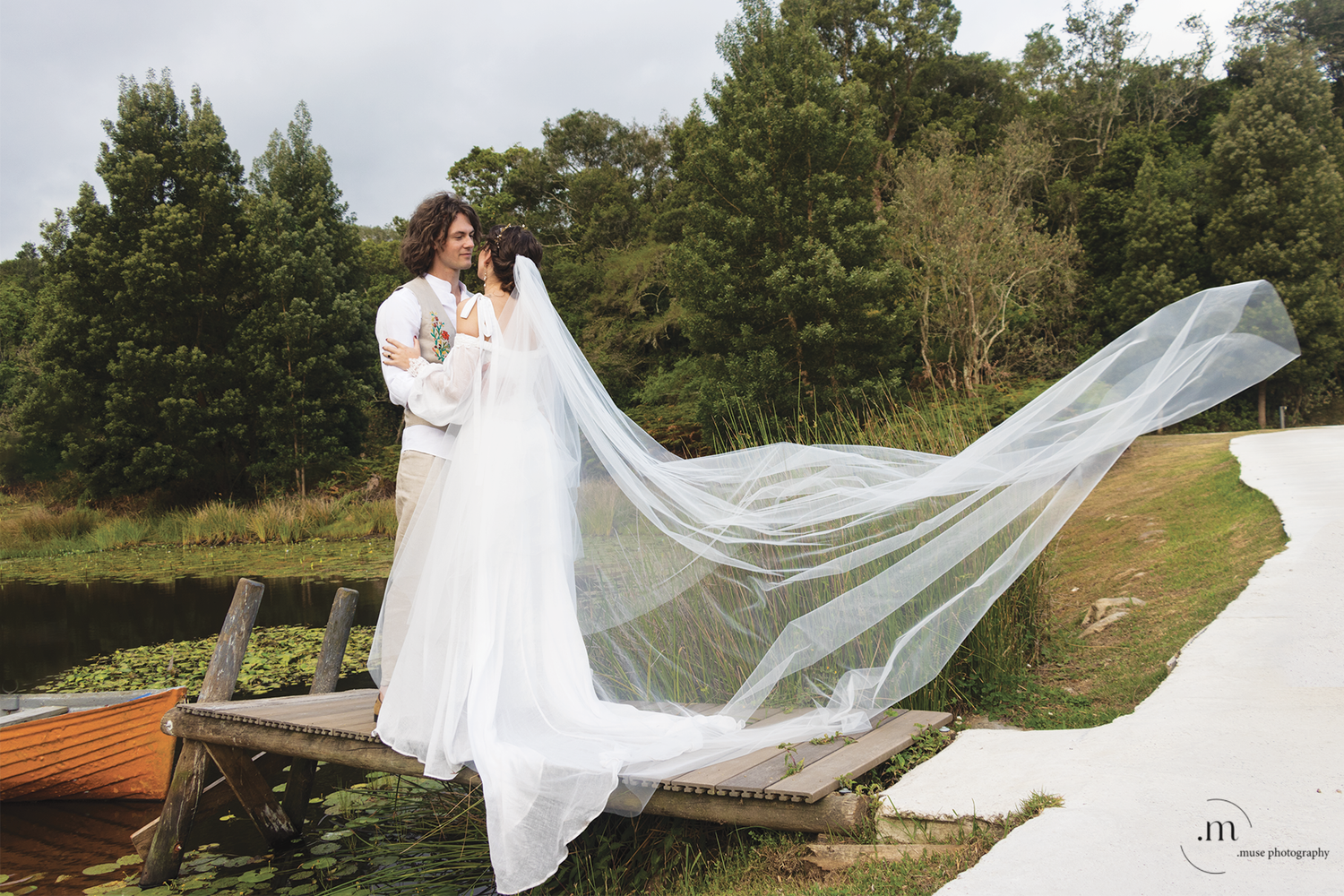 Bride and groom under the veil next to pond