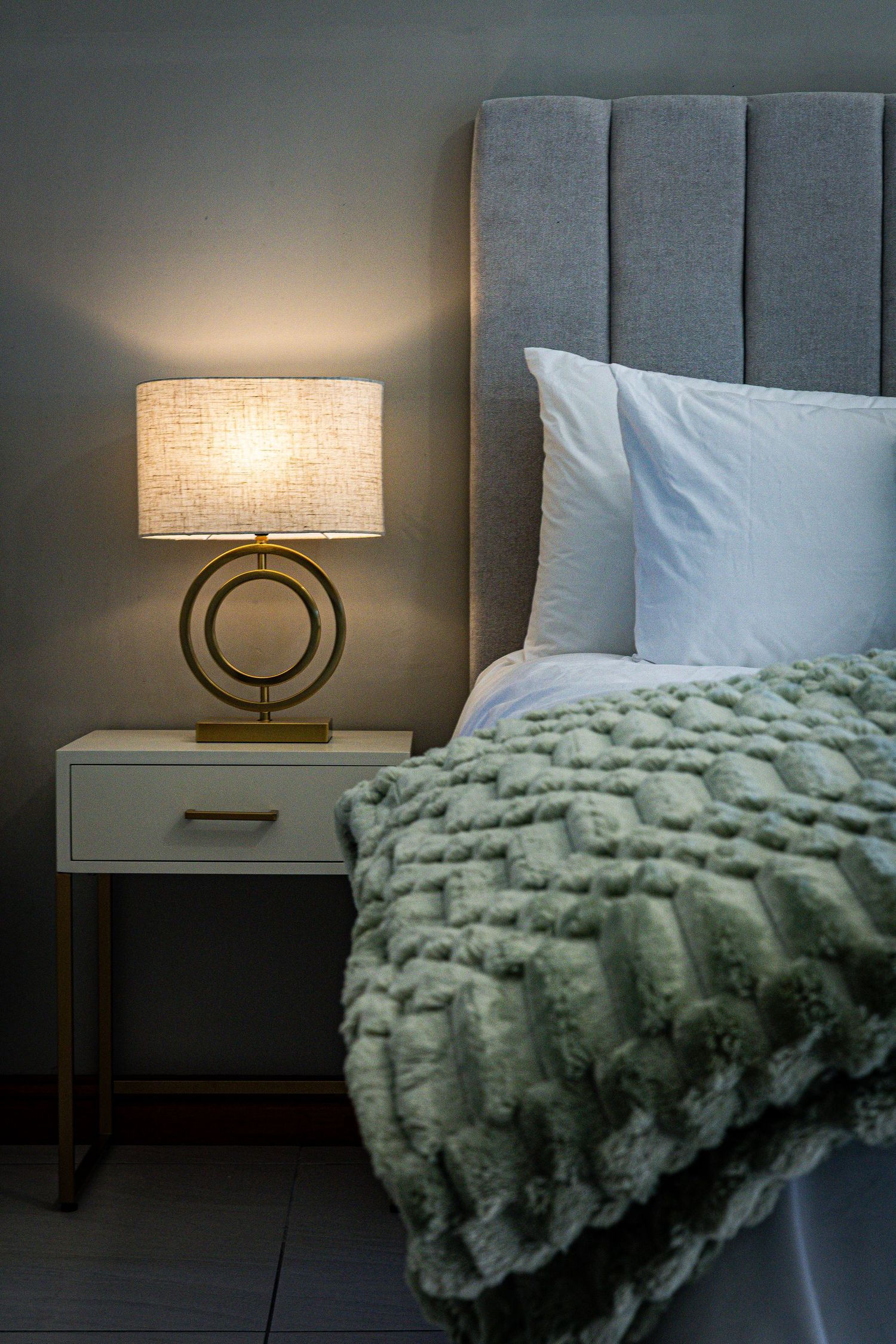 Cinematic green bed with soft bedside lamp