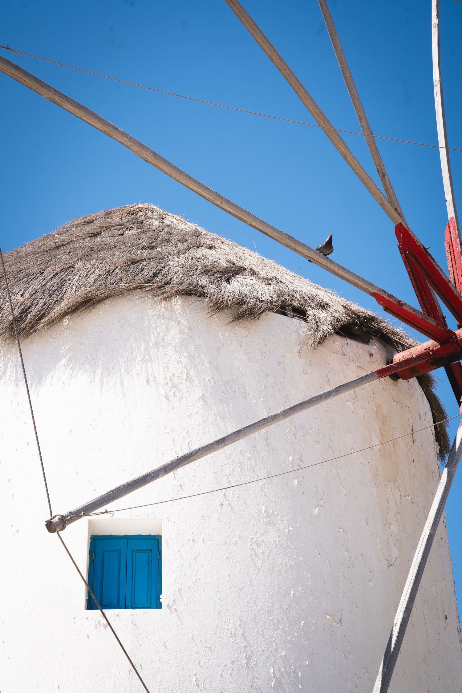 Wooden beams and white walls of traditional windmill architecture against blue sky.