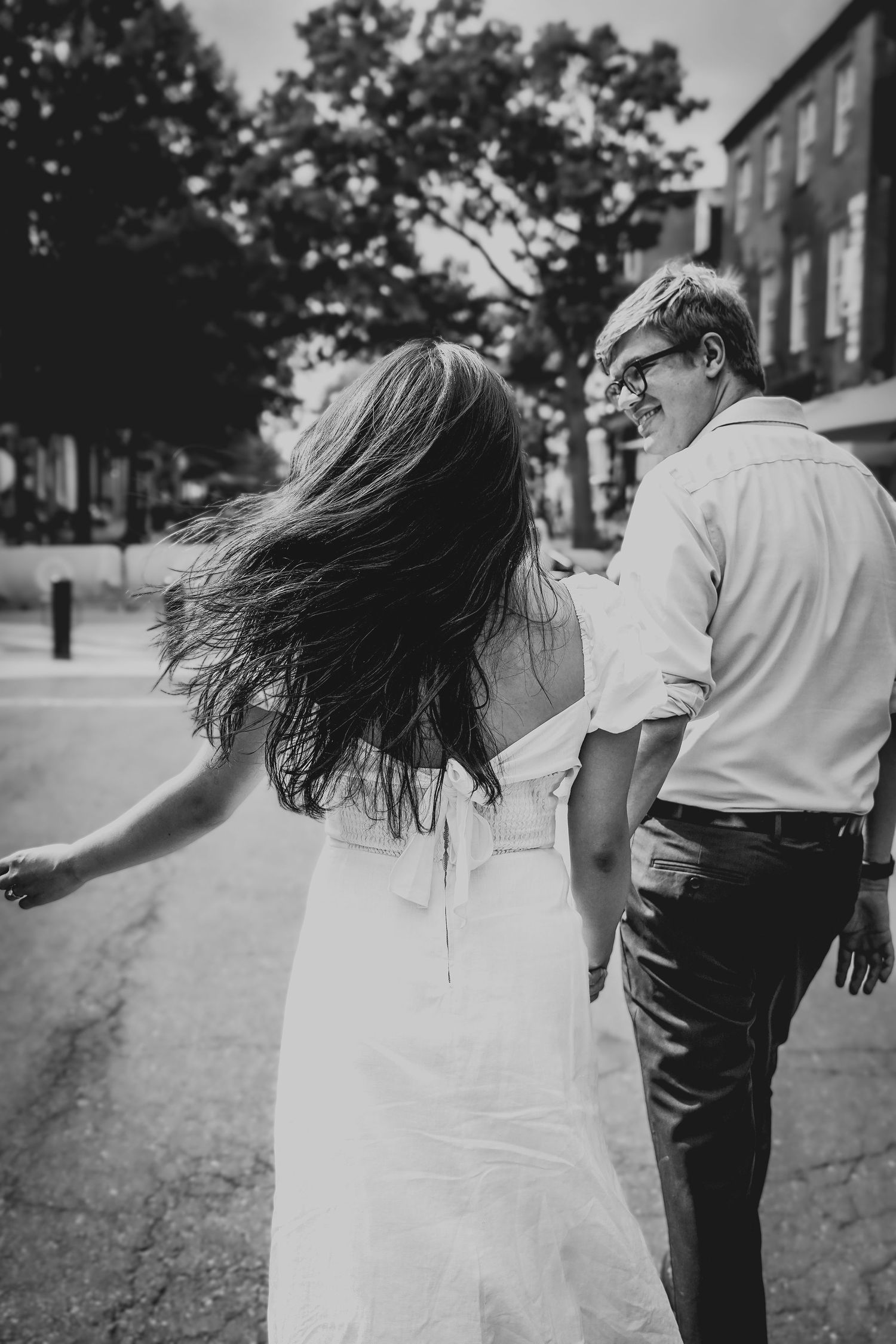 Black and white photo of couple with flowing hair walking on a street.