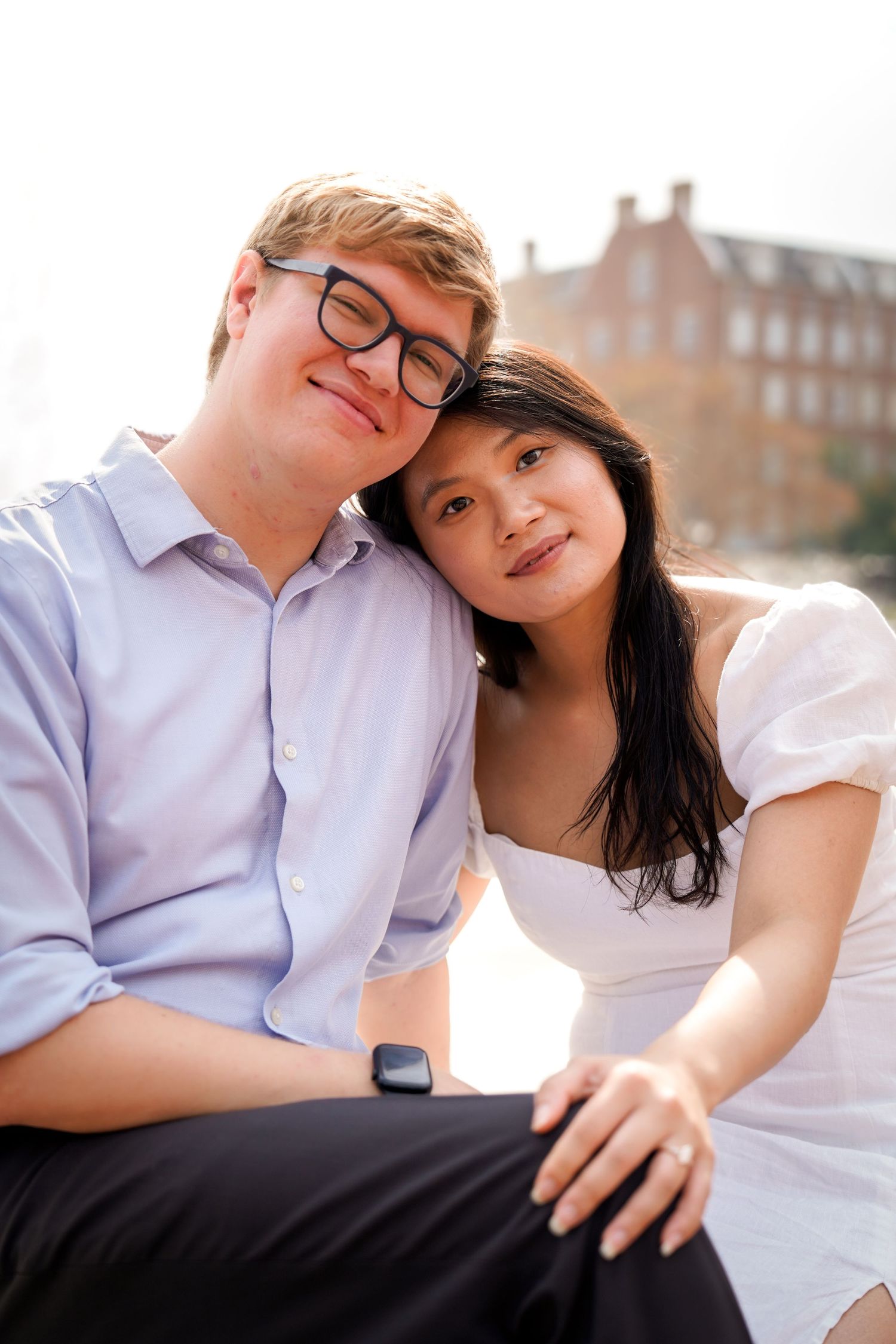 Couple in white and light blue outfits sharing tender moments against an urban backdrop.
