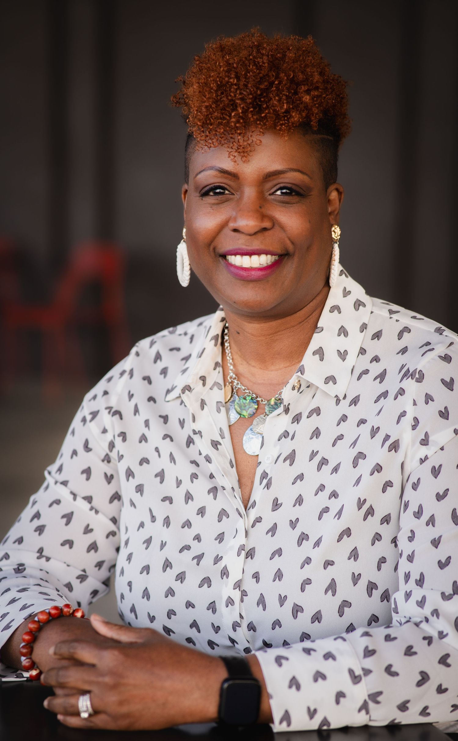 Close-up portraits showing bright jewelry and a patterned white top against a dark background.