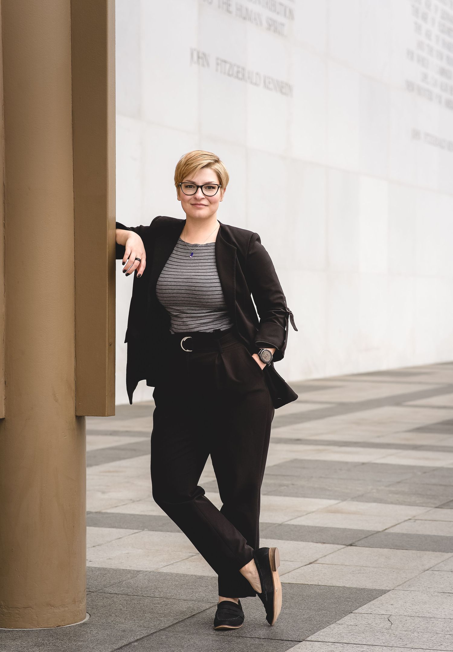 Stylish business casual look with black blazer and pants against architectural backdrop.
