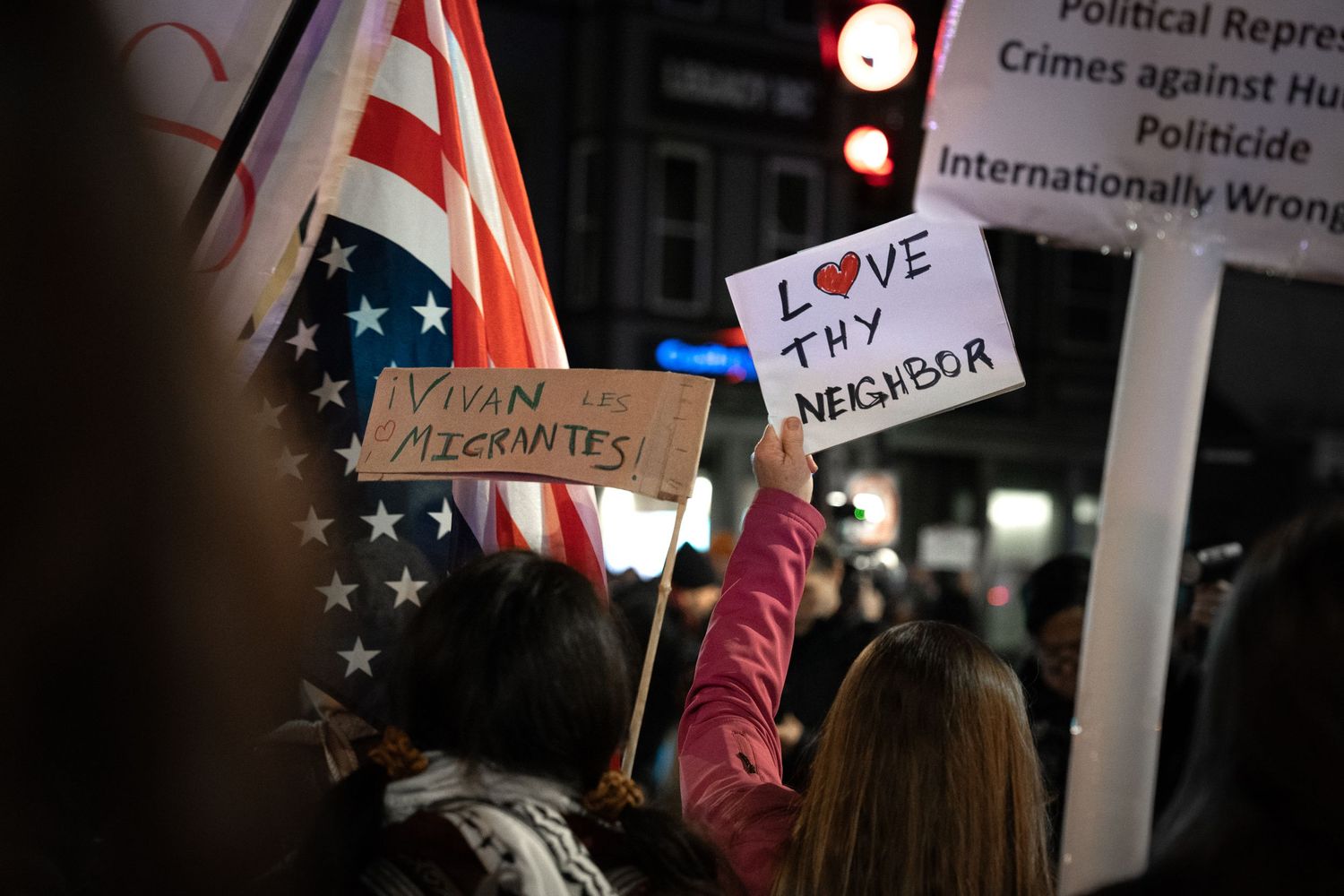 Protesters hold signs and American flags during a nighttime political demonstration against repression and crimes against humanity.