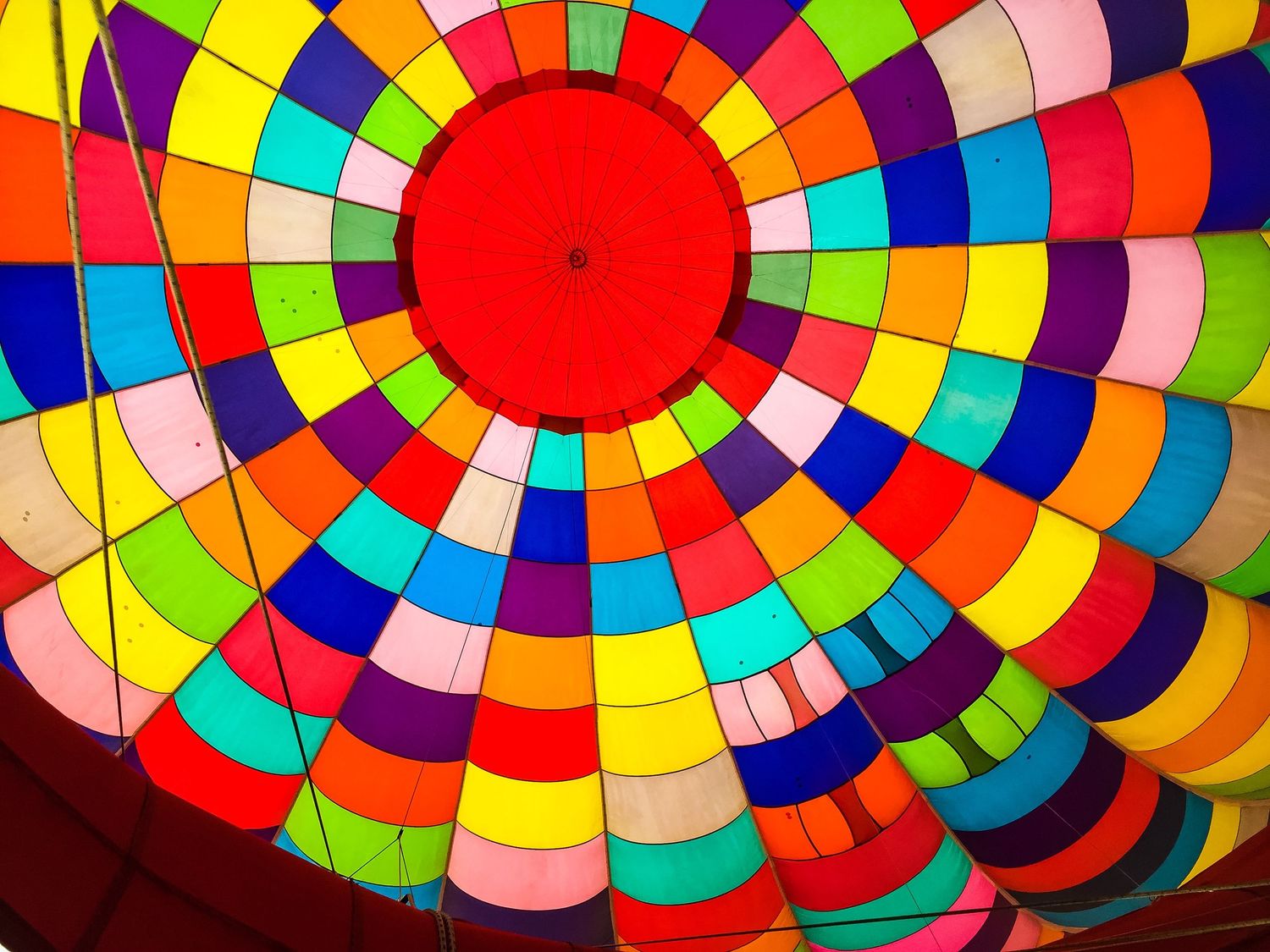 Vibrant rainbow-colored pattern of a hot air balloon interior with concentric circles radiating from a red center.