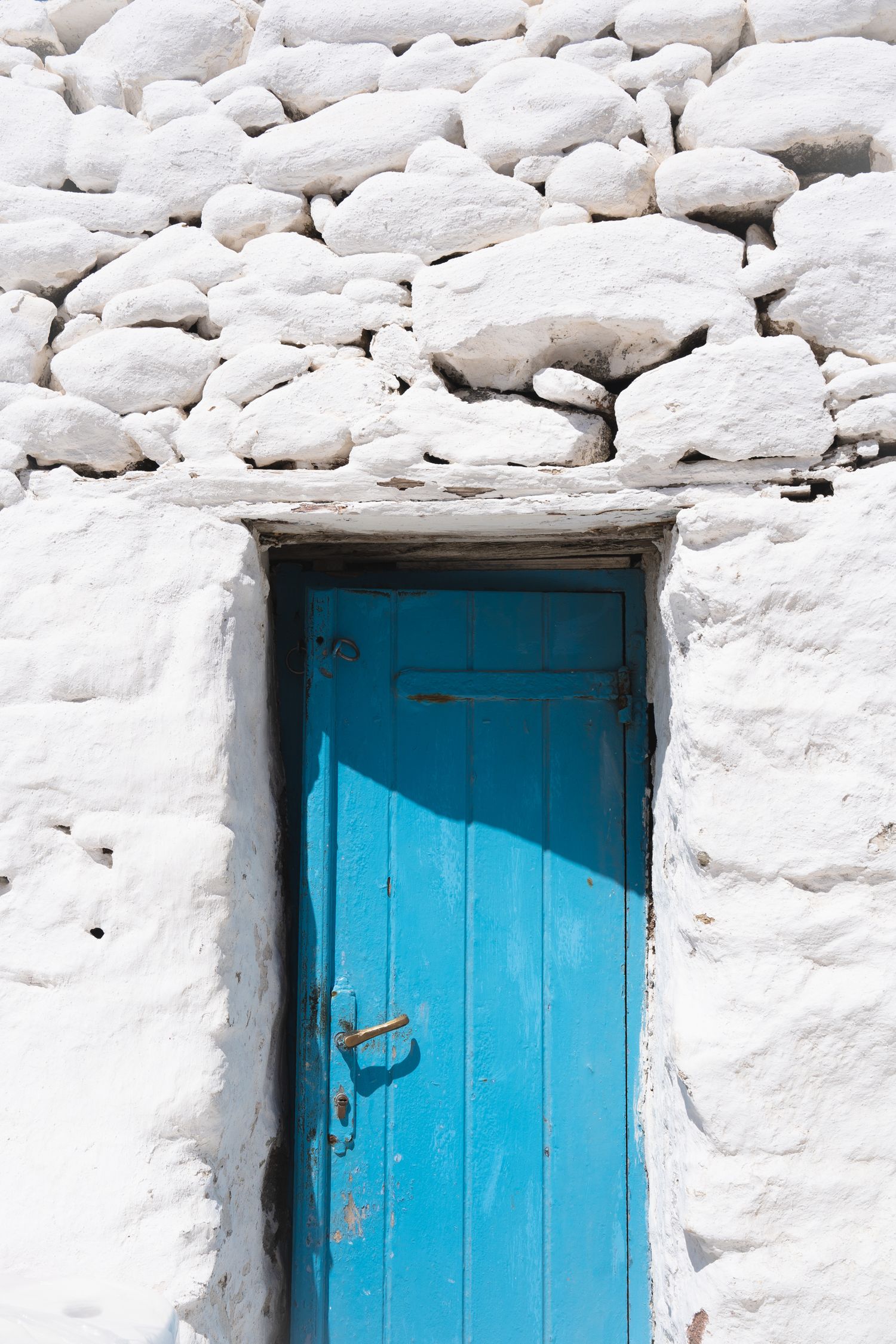 Bright blue doors set in whitewashed stone wall creating striking contrast.