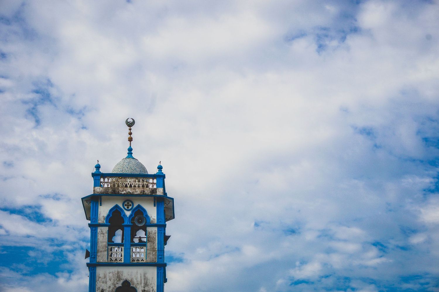 Mosque towers against a cloudy blue sky.