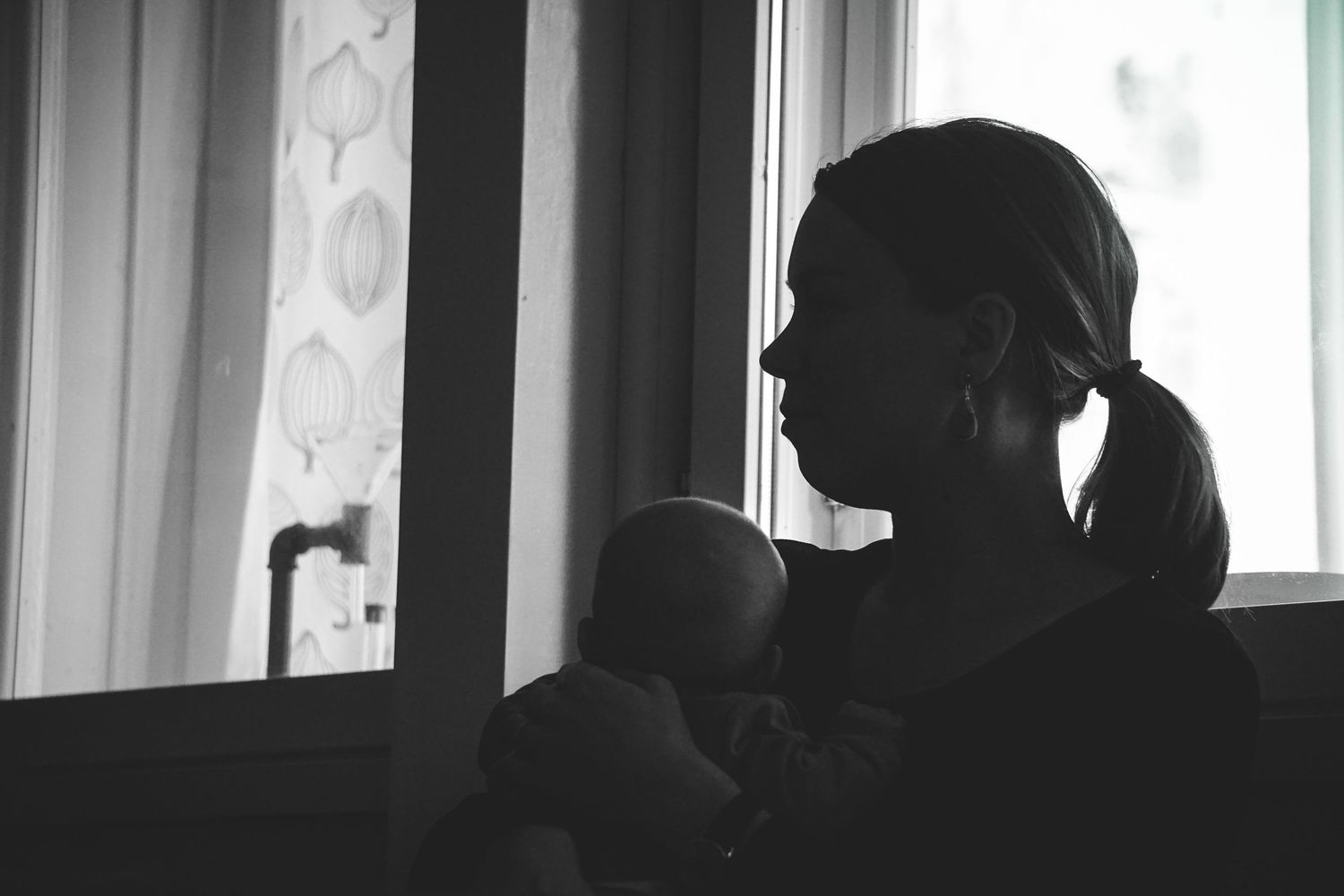Silhouettes of people against bright window background.